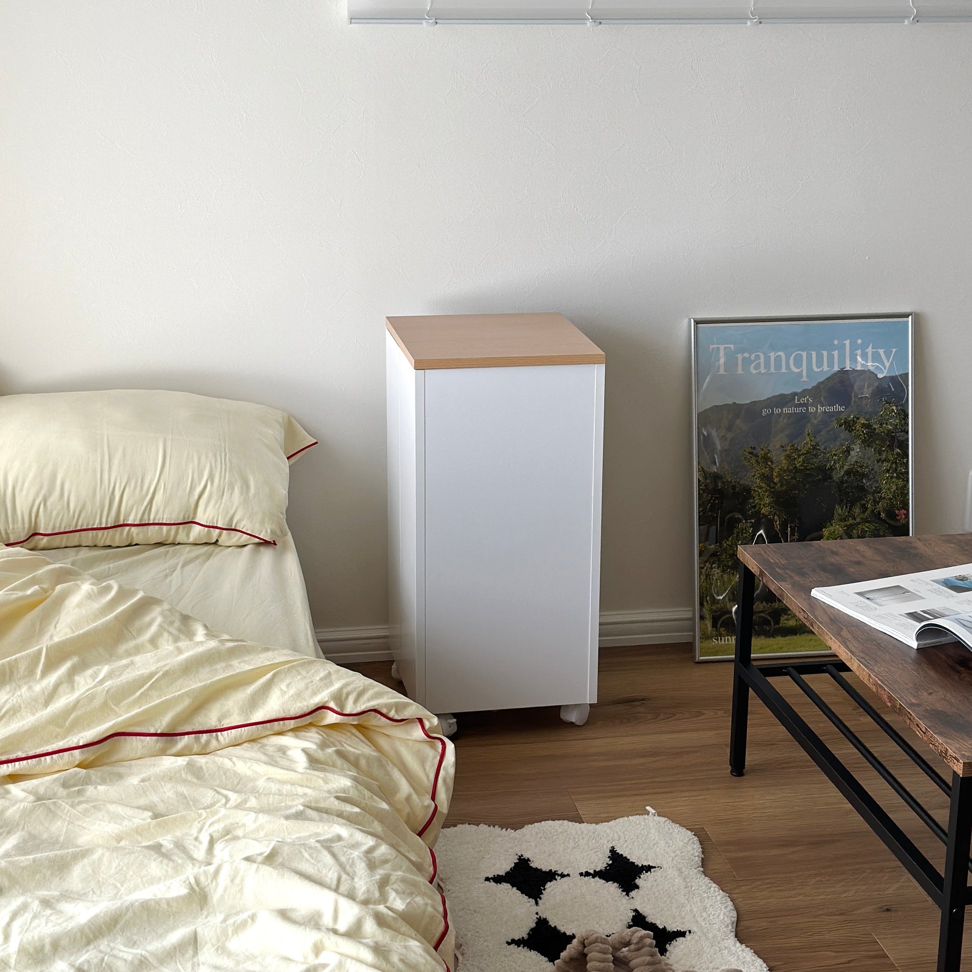 ホワイトのキャスター付きコスメワゴンをベッドサイドに置いている様子