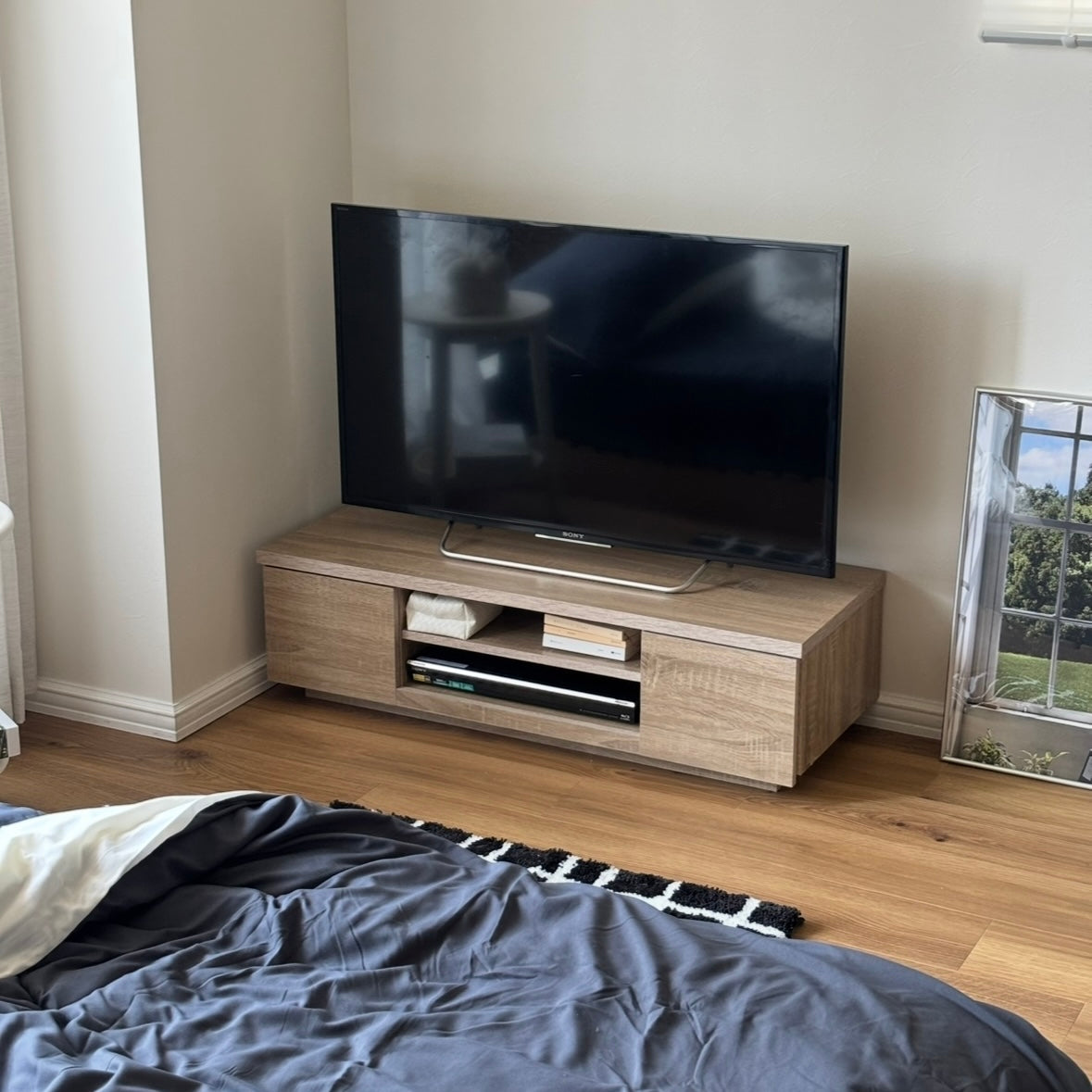 ベッドの前にホワイトオークのテレビボードを置いている様子