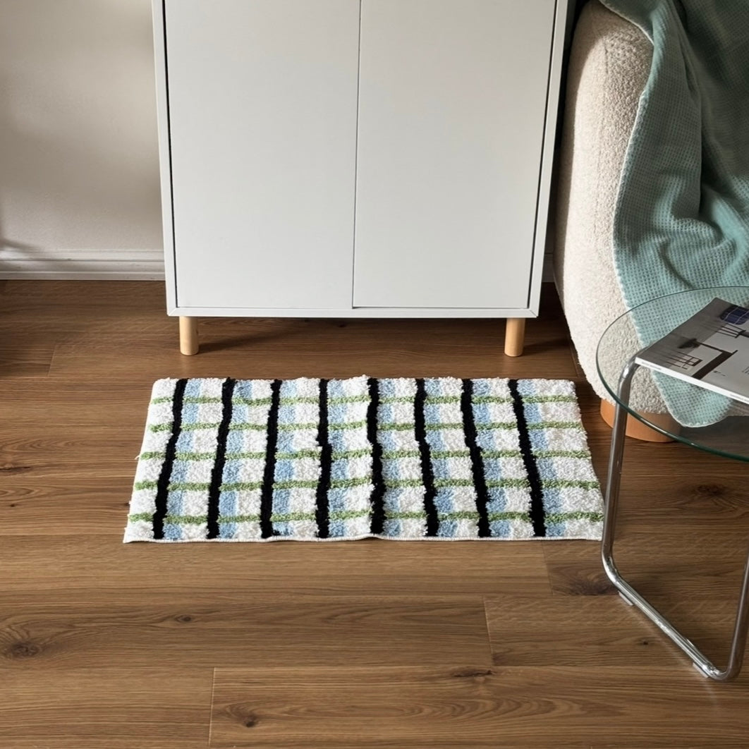 ブラックとグリーンとブルーの3色が入ったチェック柄のミニラグを白棚の前に敷いている様子