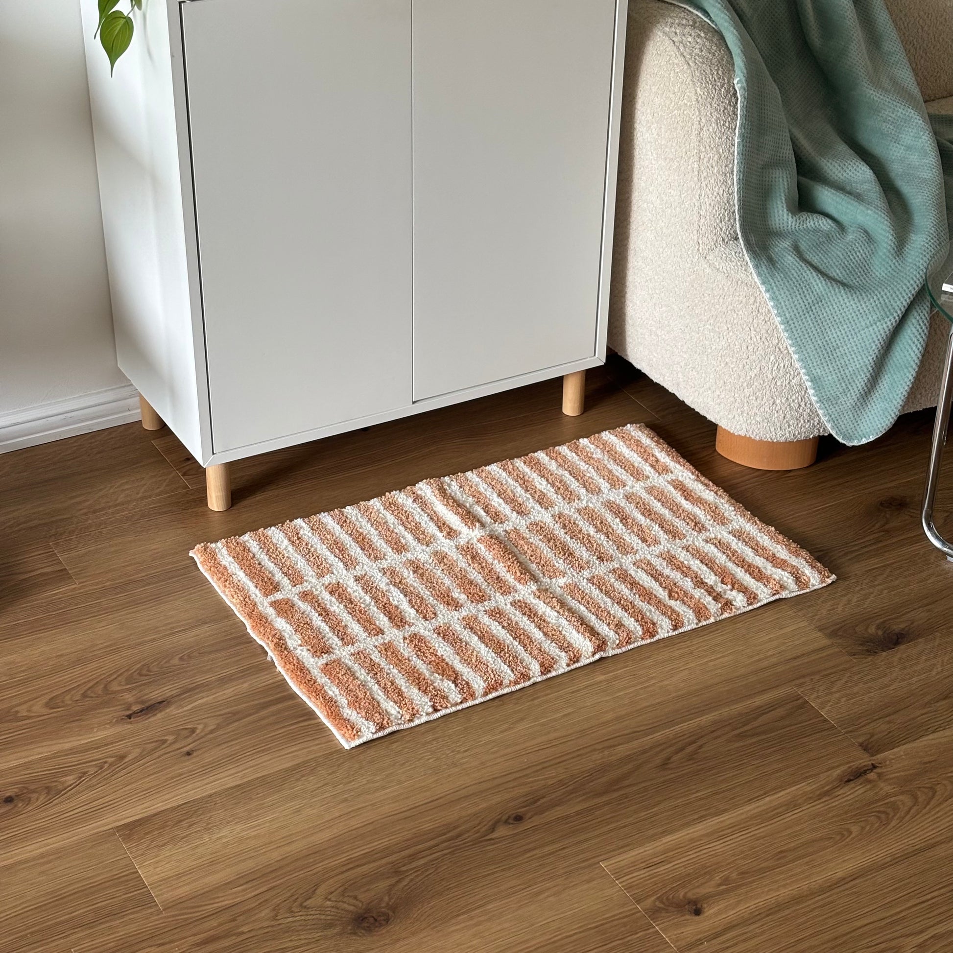 オレンジとホワイトのタイルライン柄のミニラグを白棚の前に敷いている様子