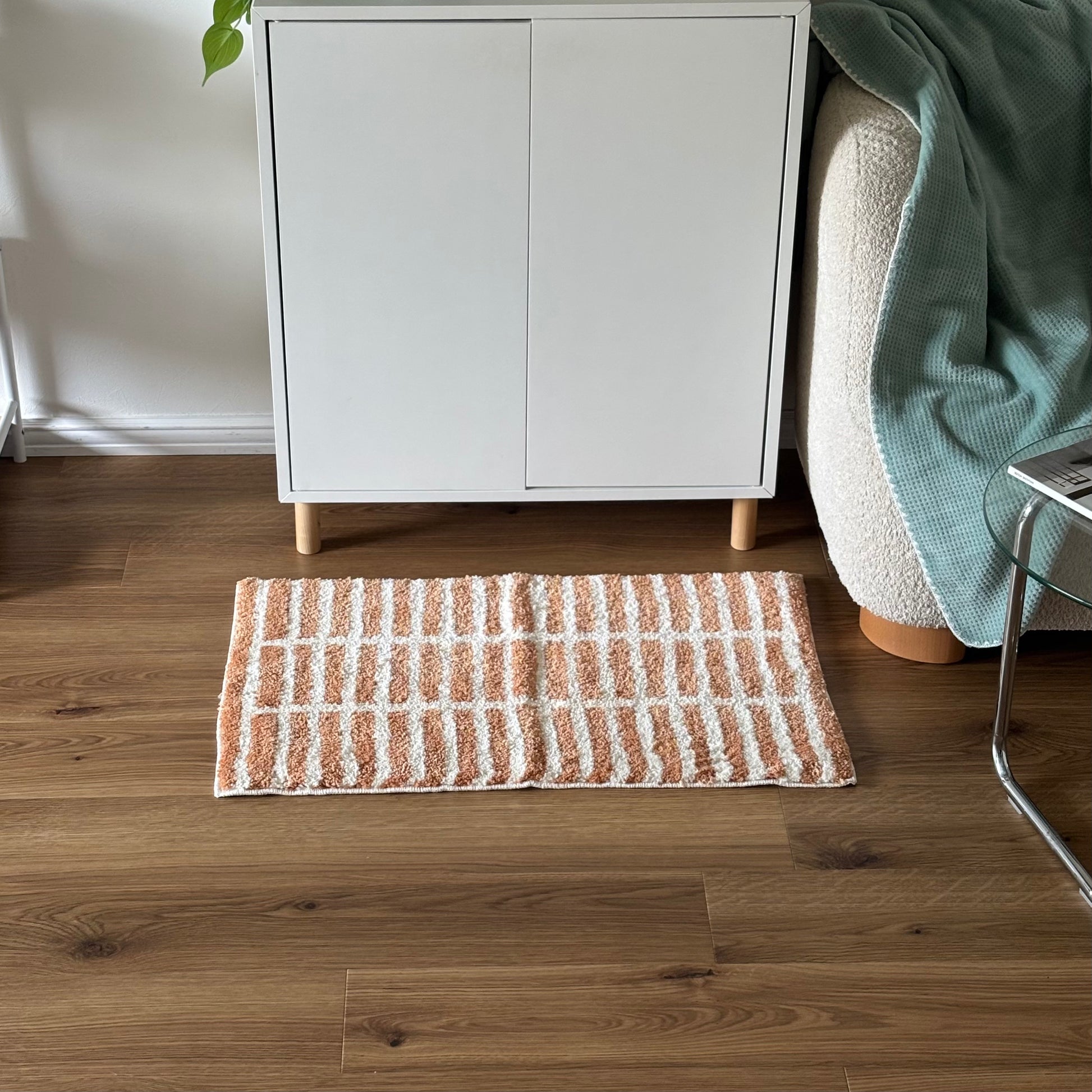 オレンジとホワイトのタイルライン柄のミニラグを白棚の前に敷いている様子