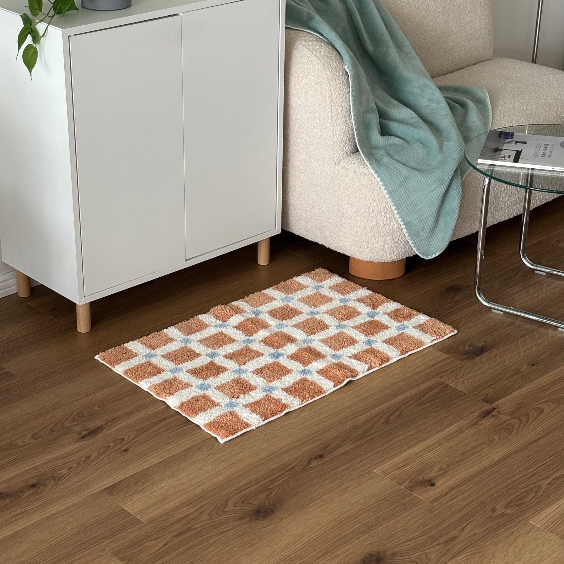 オレンジとブルーのスクエア柄のミニラグを白棚の前に敷いている様子