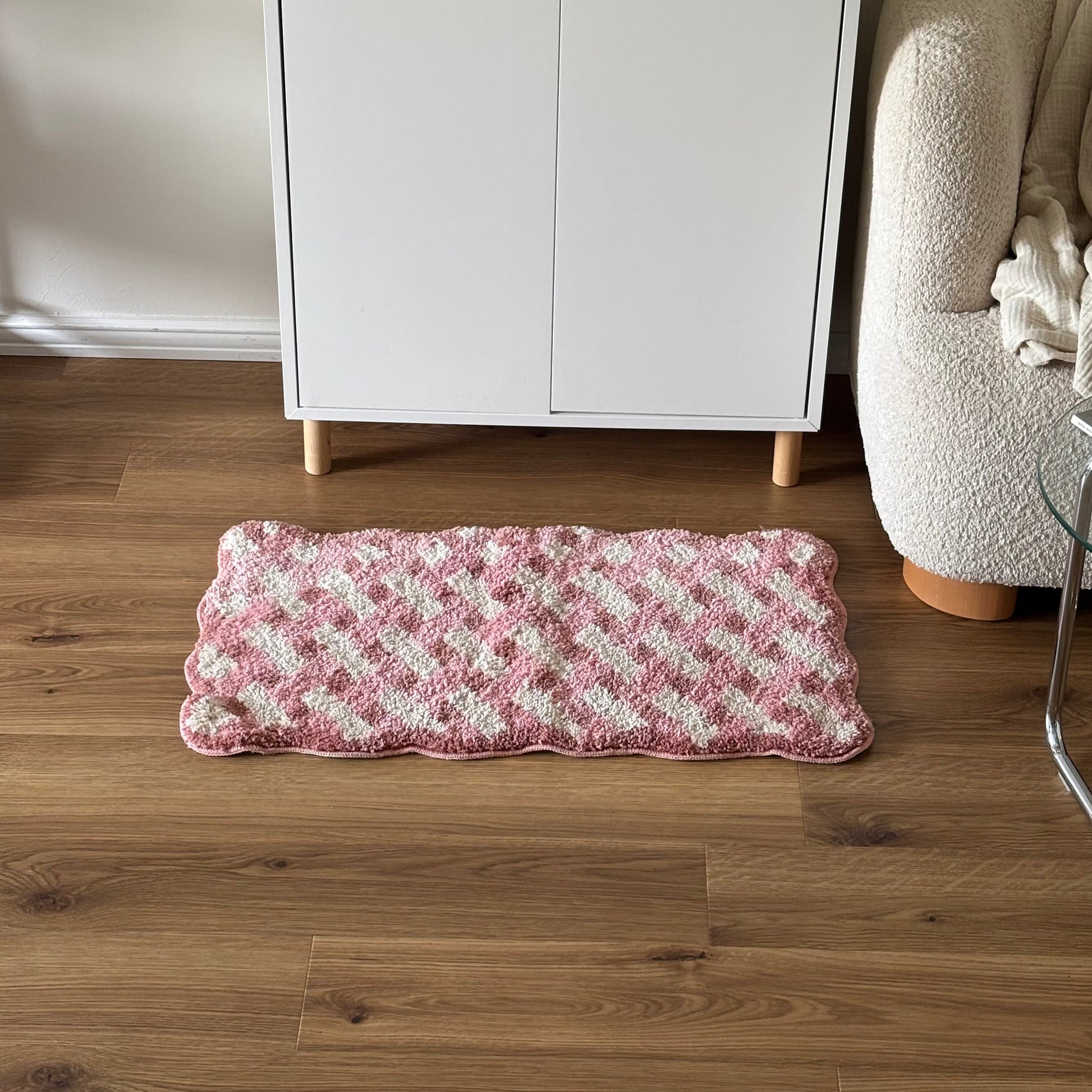 ピンクのウェーブクロス柄のミニラグを白棚の前に敷いている様子