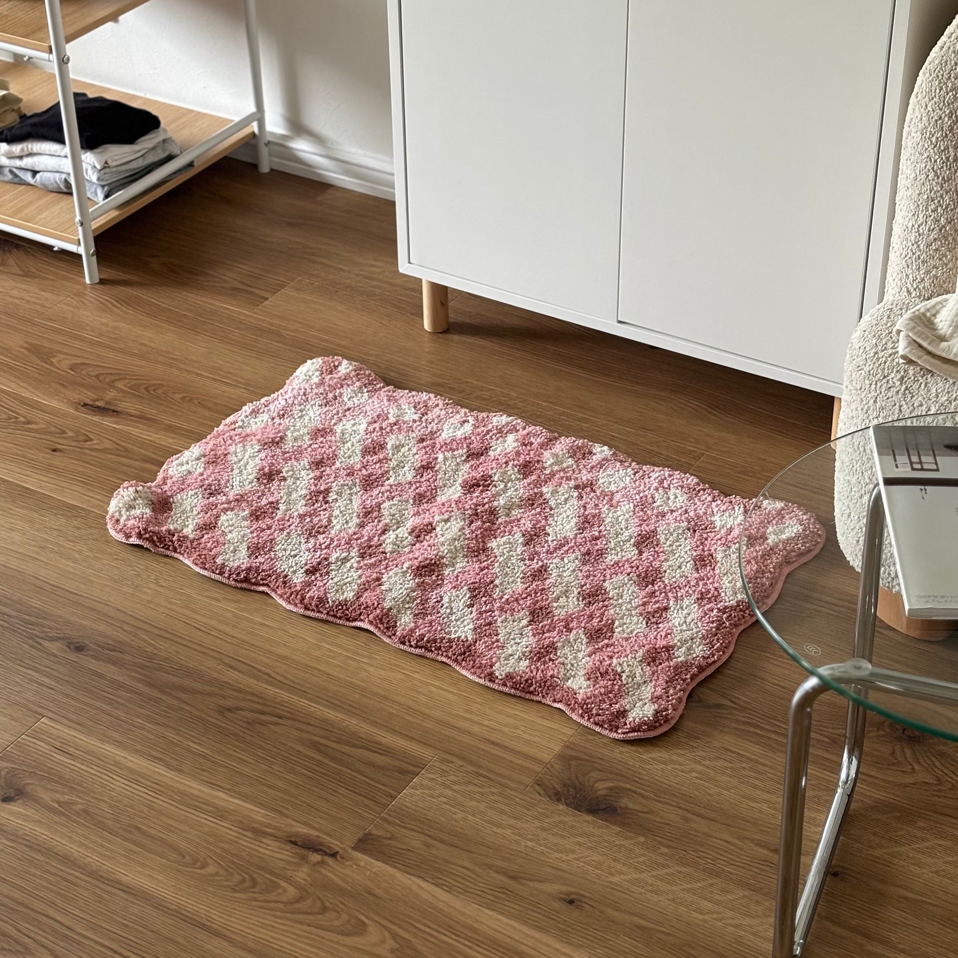 ピンクのウェーブクロス柄のミニラグを白棚の前に敷いている様子