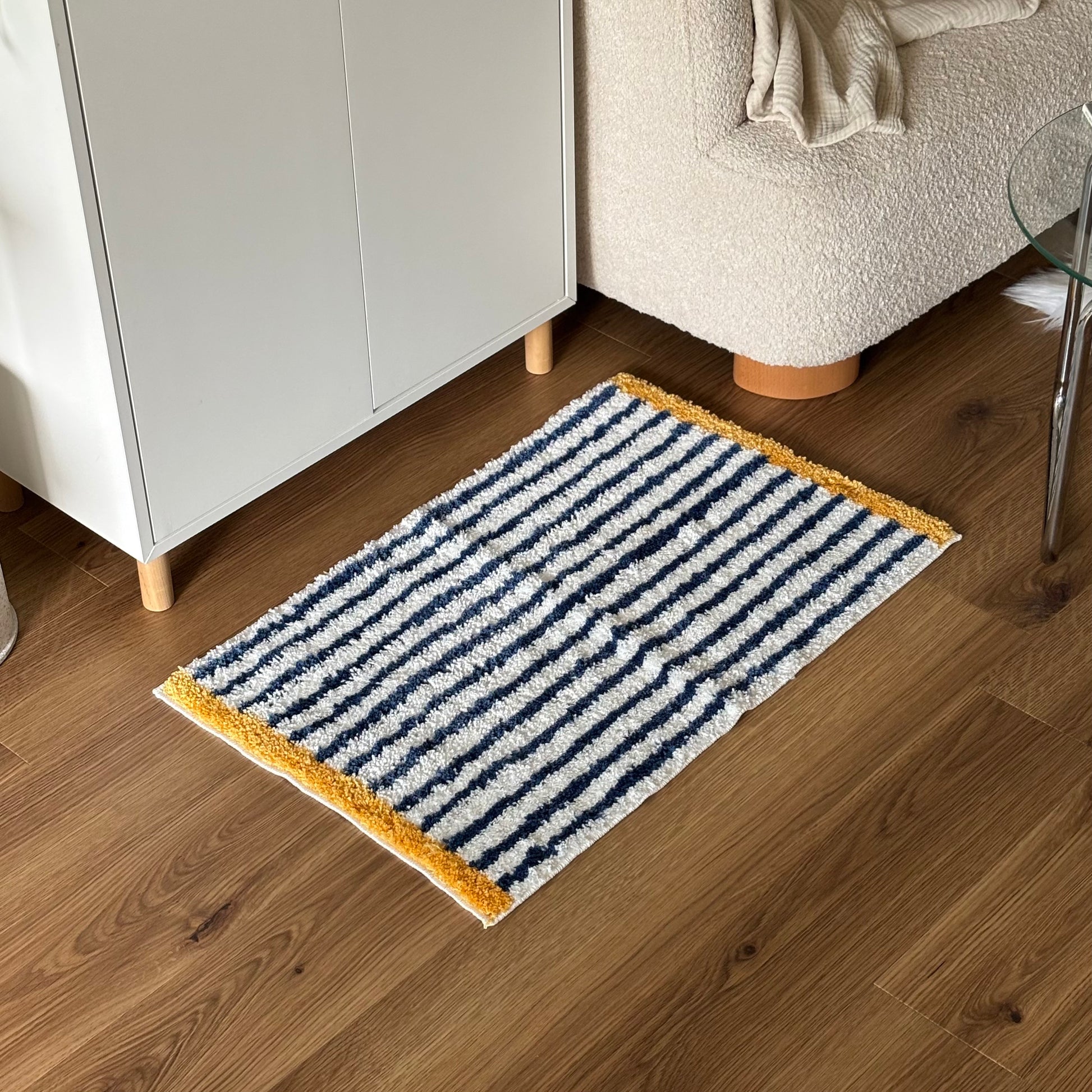 ブルーのボーダーとイエローの縁取りのミニラグを部屋に置いている様子