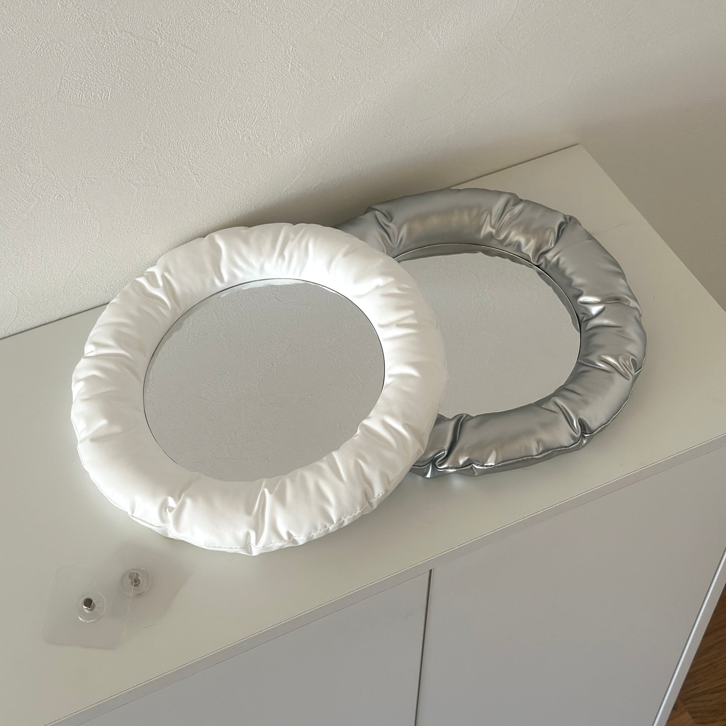 ホワイトとシルバーのもちもちのクッションが周りについたミラーが並んで置かれている様子