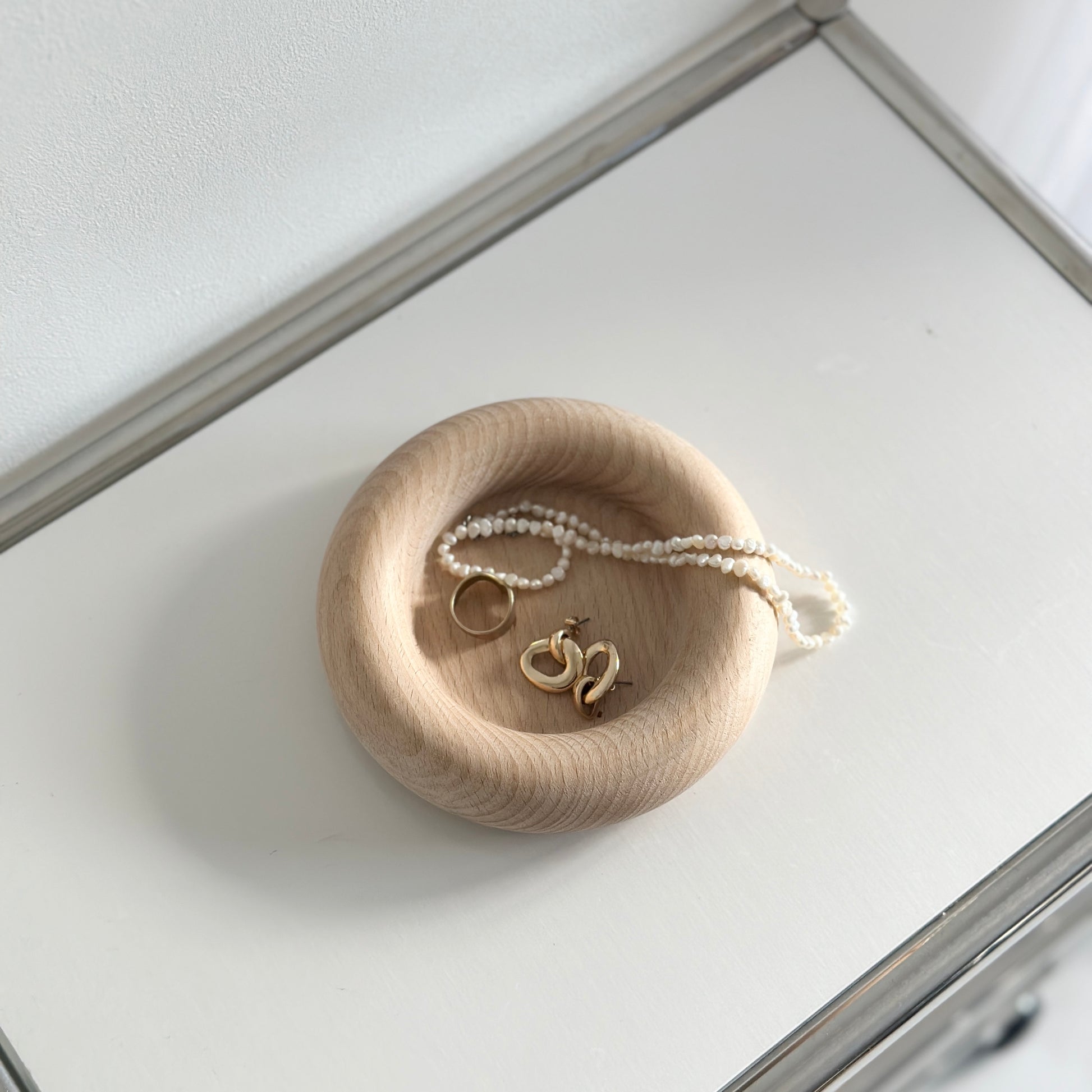 フチがぽってりした木製プレートの中にアクセサリーが入れられている