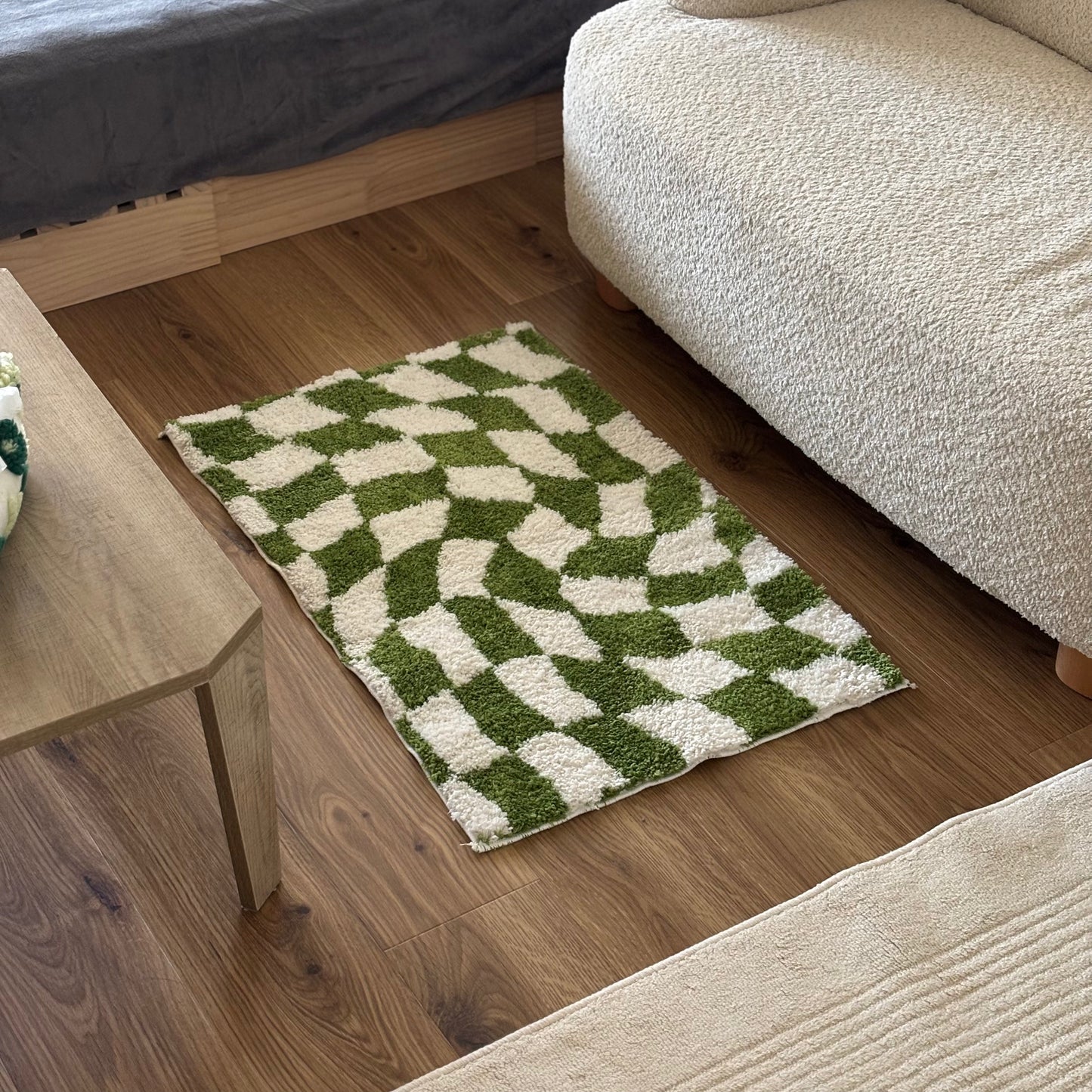 緑と白のグリッド柄のミニラグをソファの前に敷いている様子