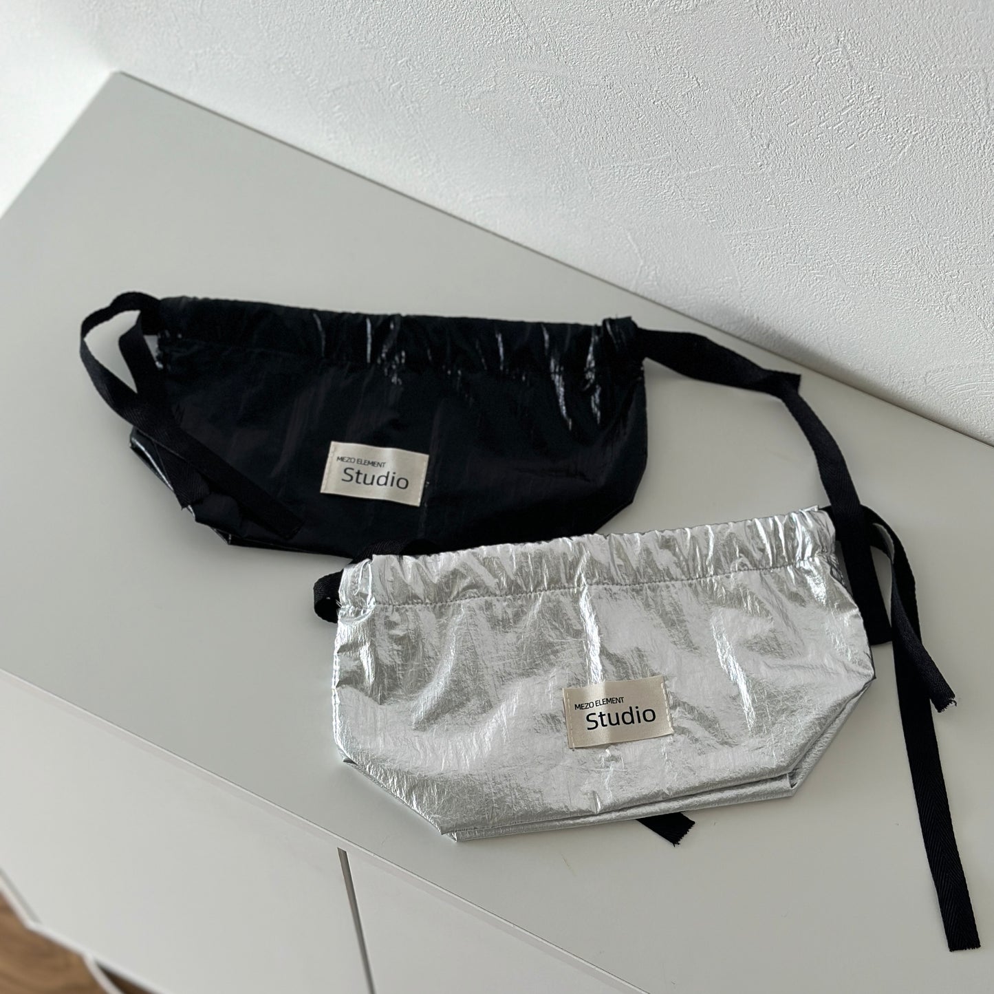 シルバーとブラックのティッシュケースが白い棚の上に置かれている様子