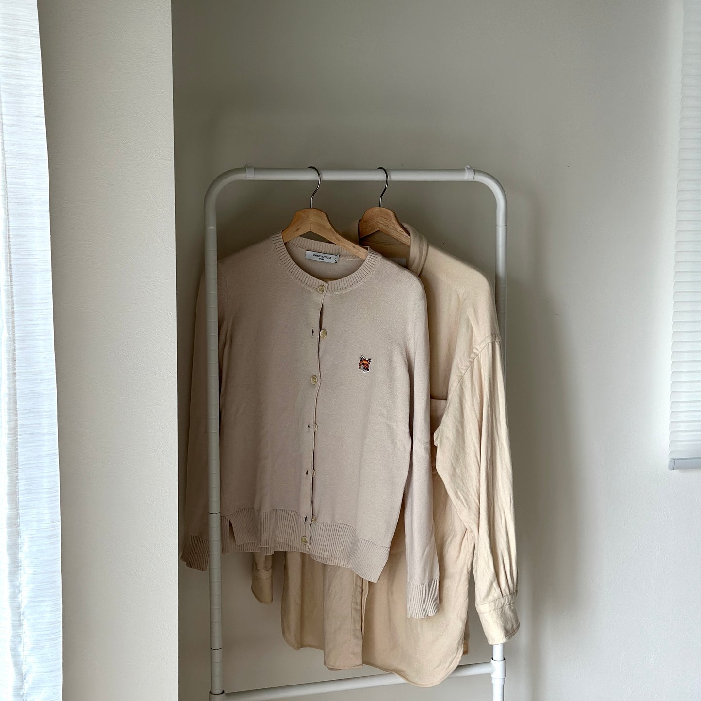 ホワイトのキャスター付きのハンガーラックにベージュの服がかかっている様子