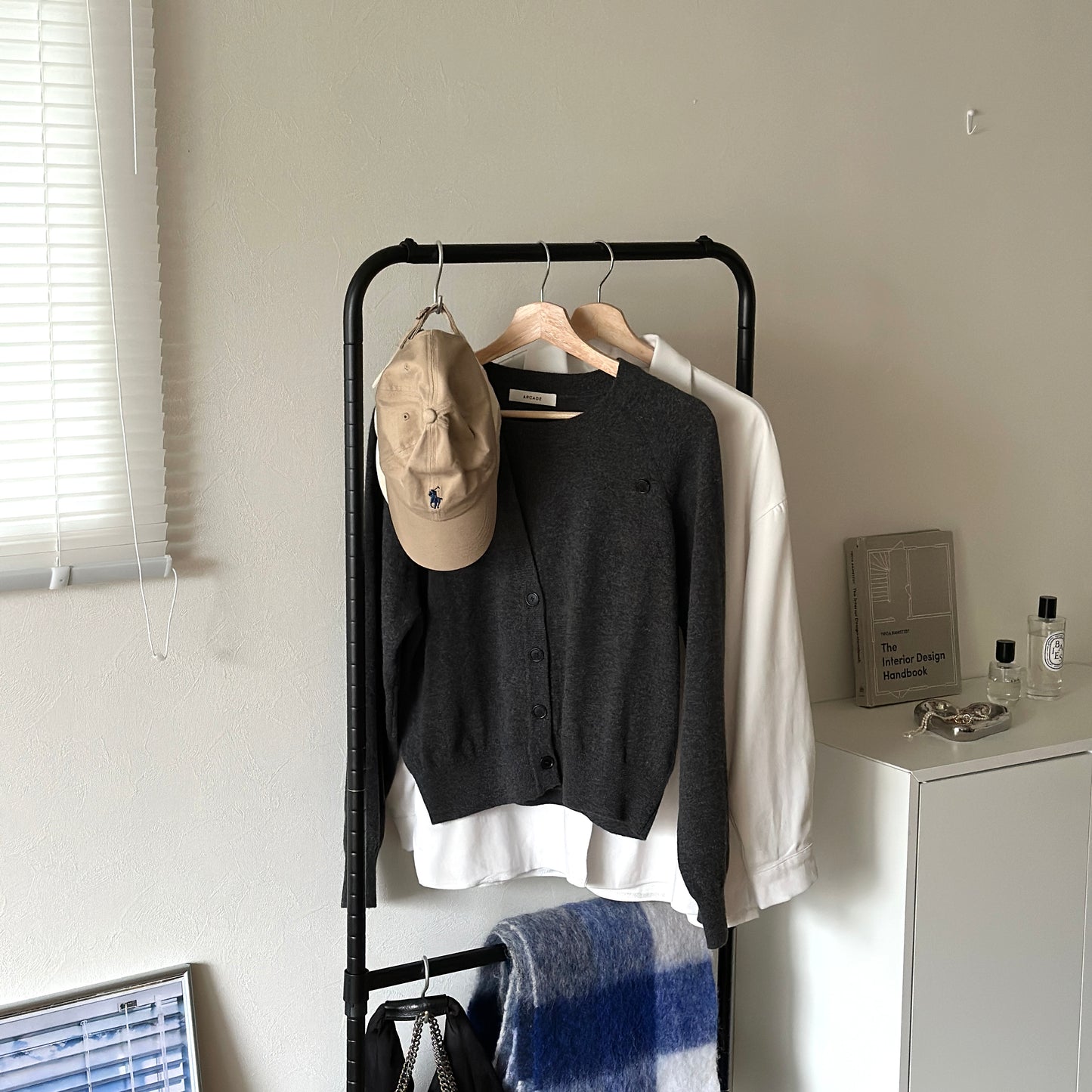 ブラックのキャスター付きのハンガーラックに服が掛かっている様子