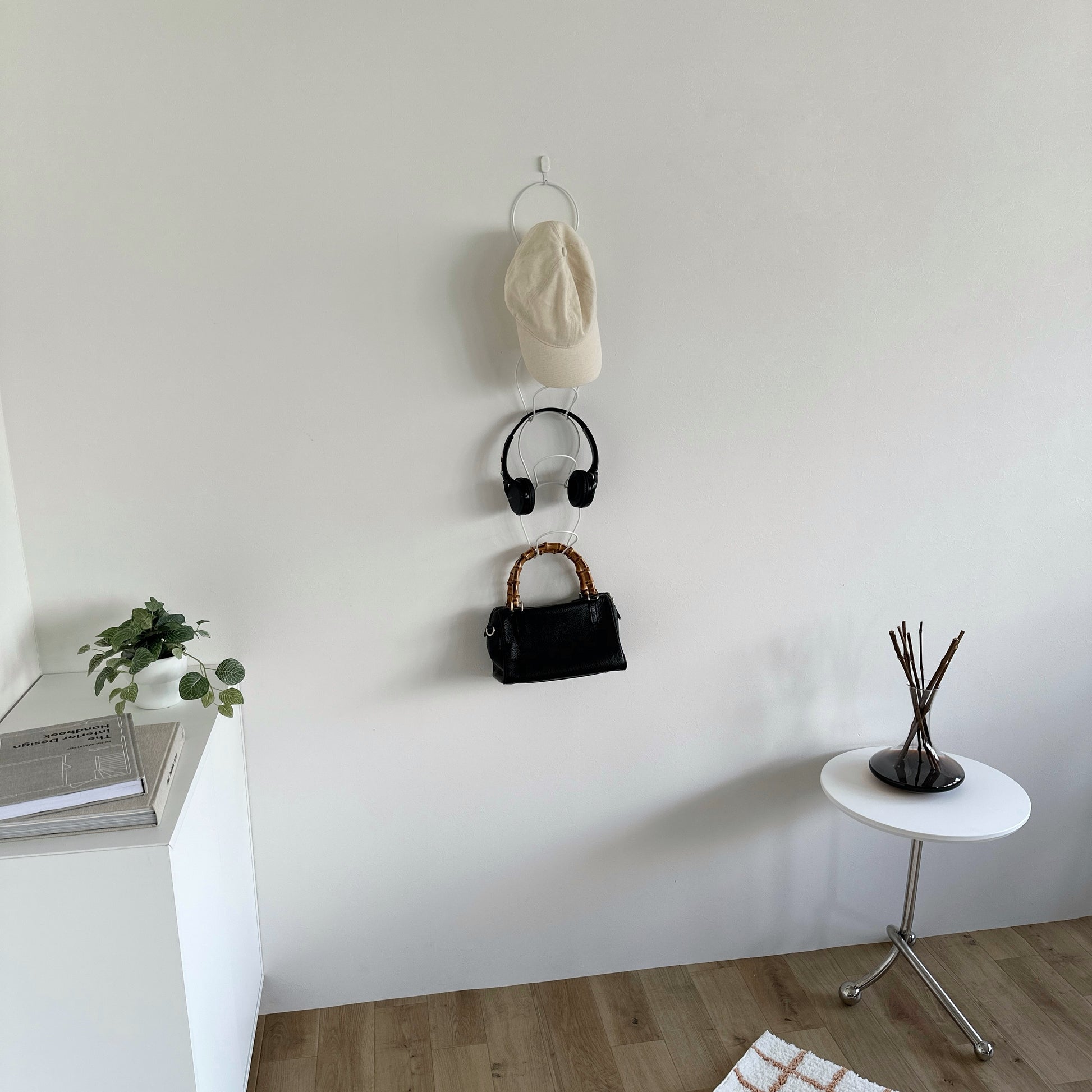 ホワイトの帽子掛けハンガーに帽子やヘッドホン、バッグが掛かっている
