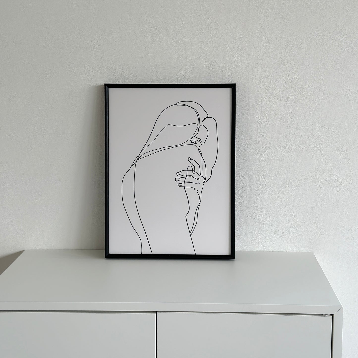 女性が振り向いた姿が描かれたラインアートが白棚の上に置かれてある