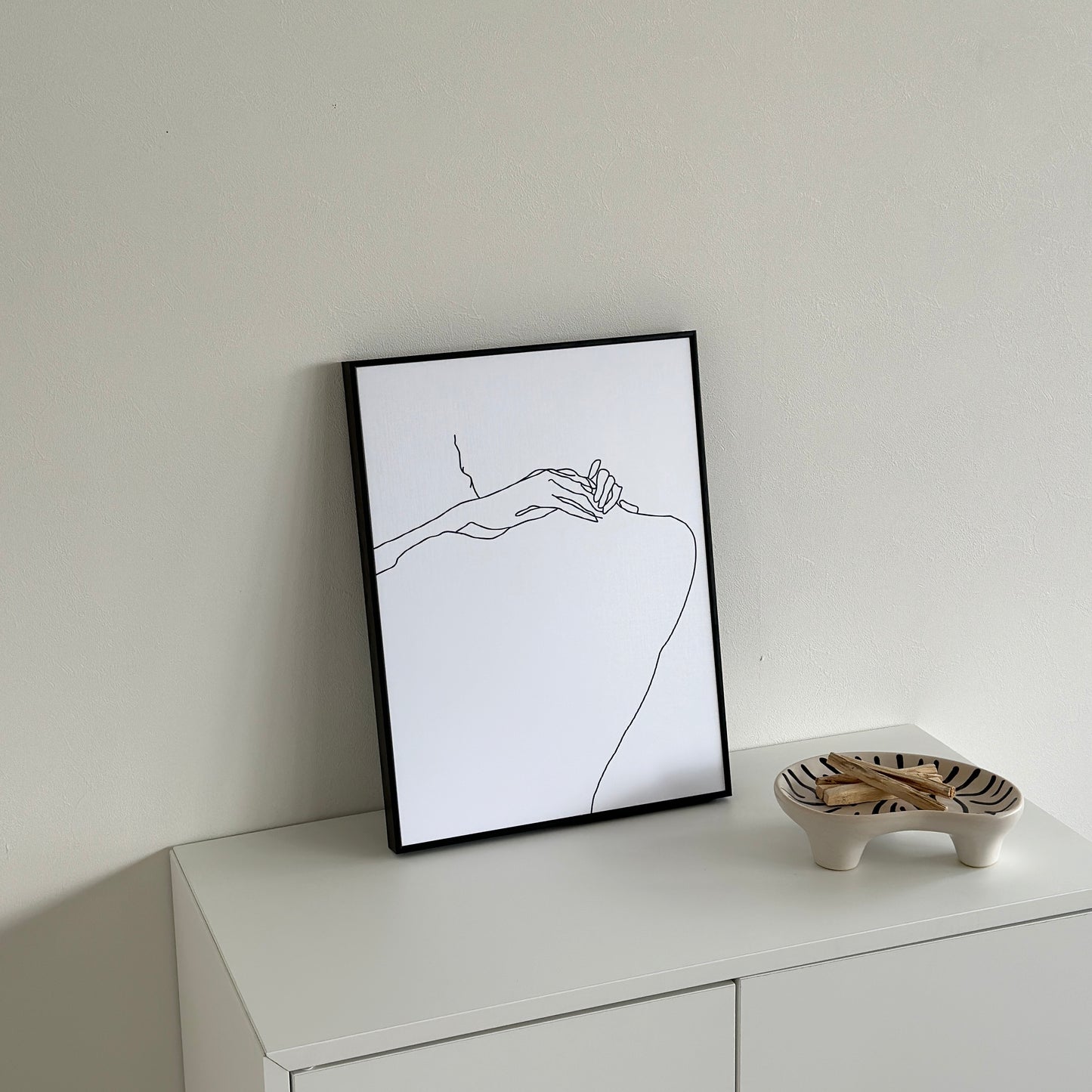 ニュアンスライン後ろ姿が描かれたアートが棚の上に置かれている