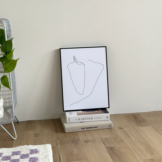 ラインアートで頬杖をする姿が描かれたアートが床の上に置かれている様子