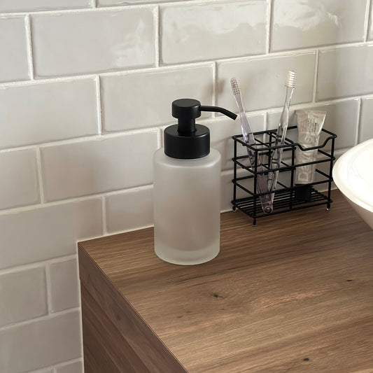 マットガラスとブラックポンプのソープディスペンサーが洗面台に置かれている様子