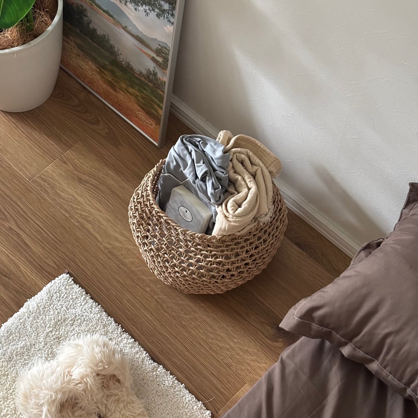 ラウンドのペーパーコードバスケットにパジャマや文庫本、ブランケットを入れている様子