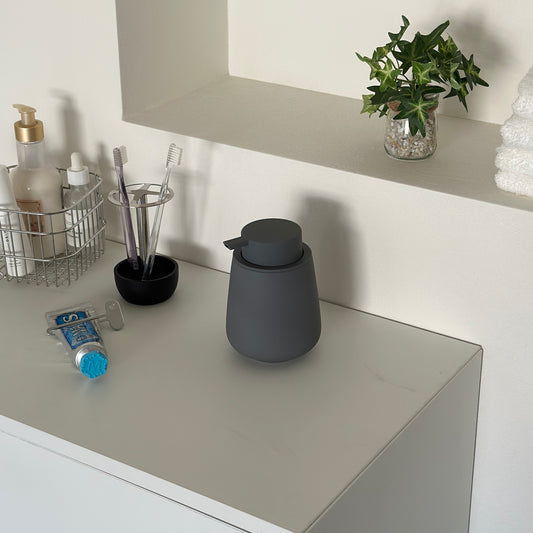 グレーのころんとしたシルエットが可愛い泡タイプのソープボトルが洗面台に置かれている様子