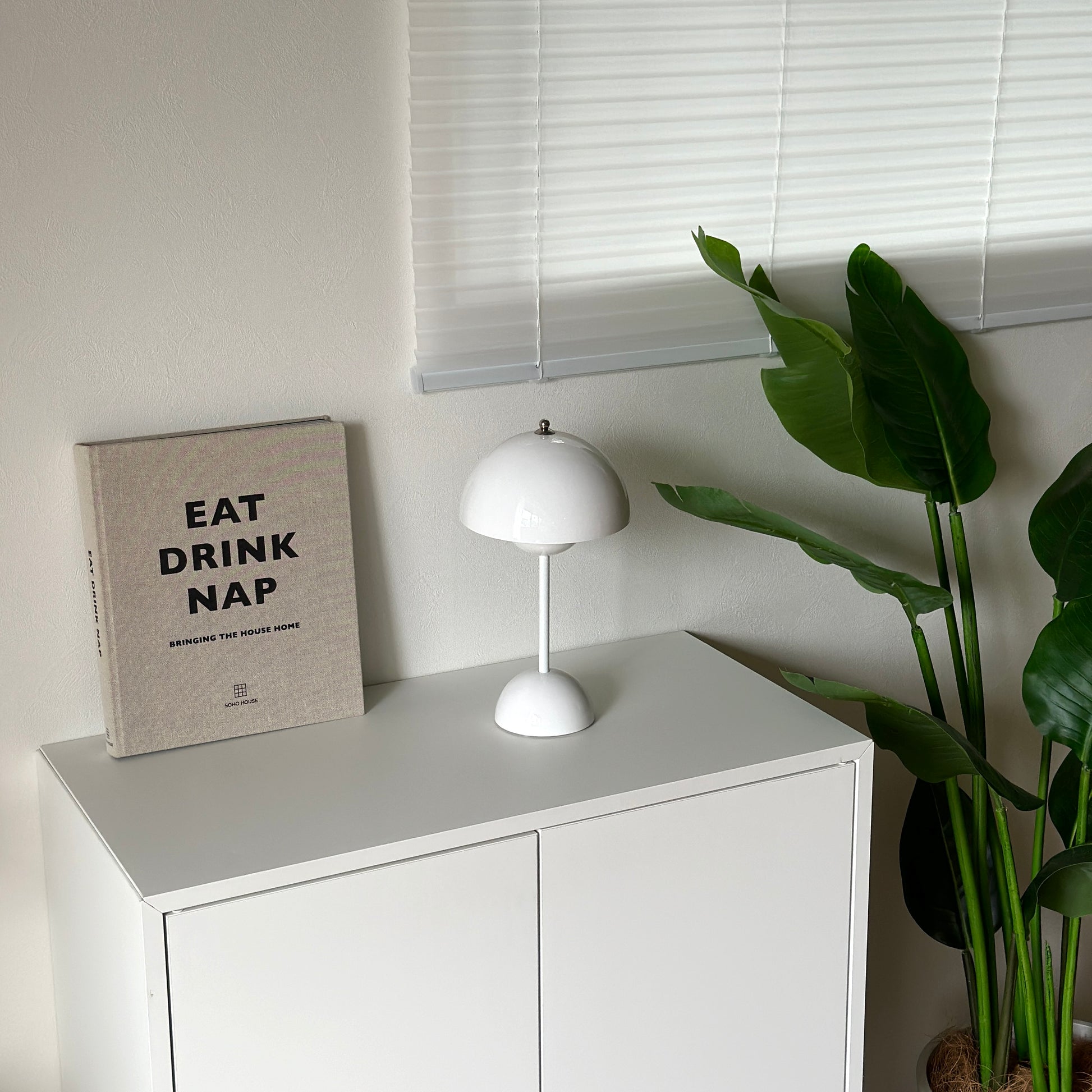 棚の上に乗せられた半球型のシルエットが特徴的なホワイトのテーブルライトと1冊の本