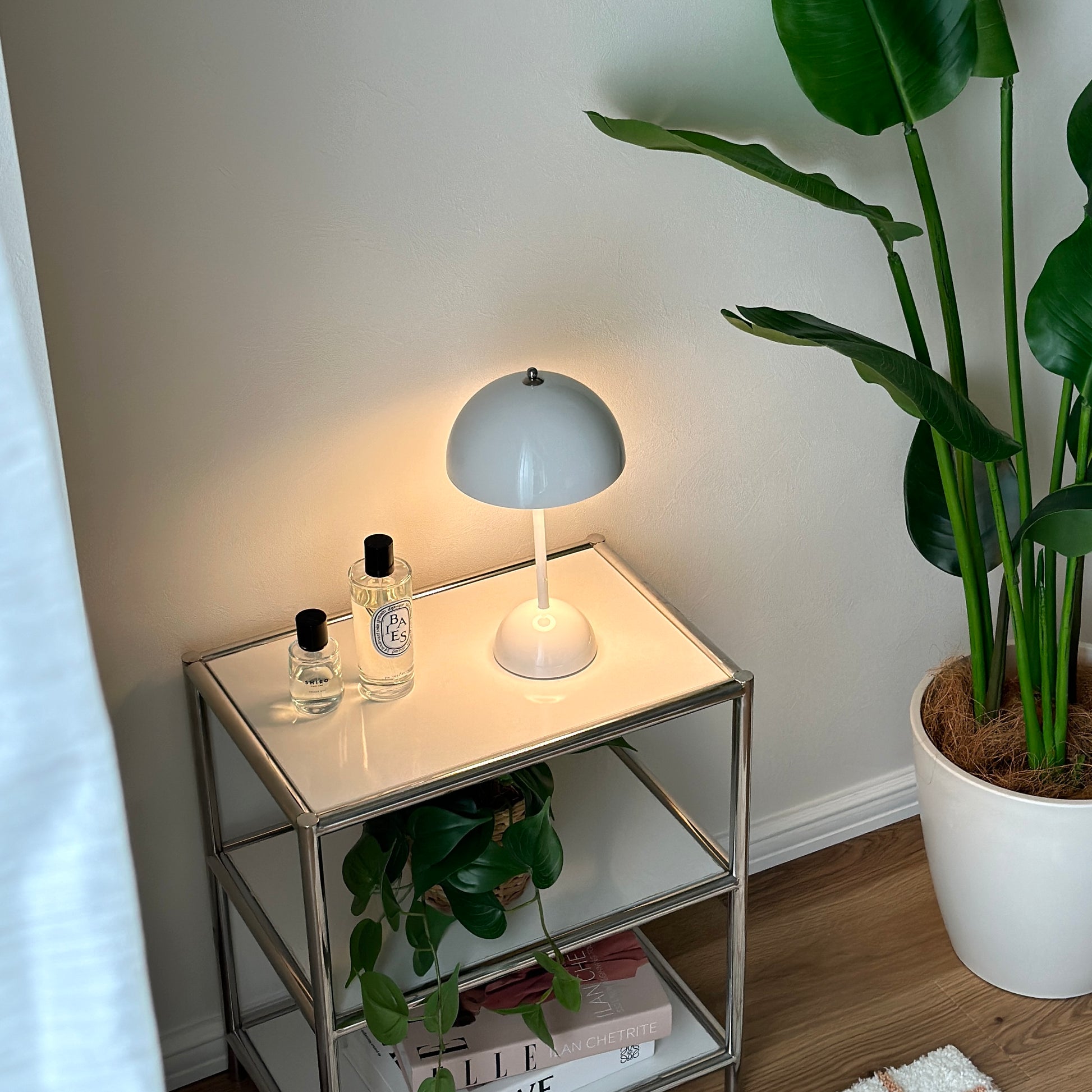 シェルフの上に乗せられた半球型のシルエットが特徴的なホワイトのテーブルライトと香水が2つ