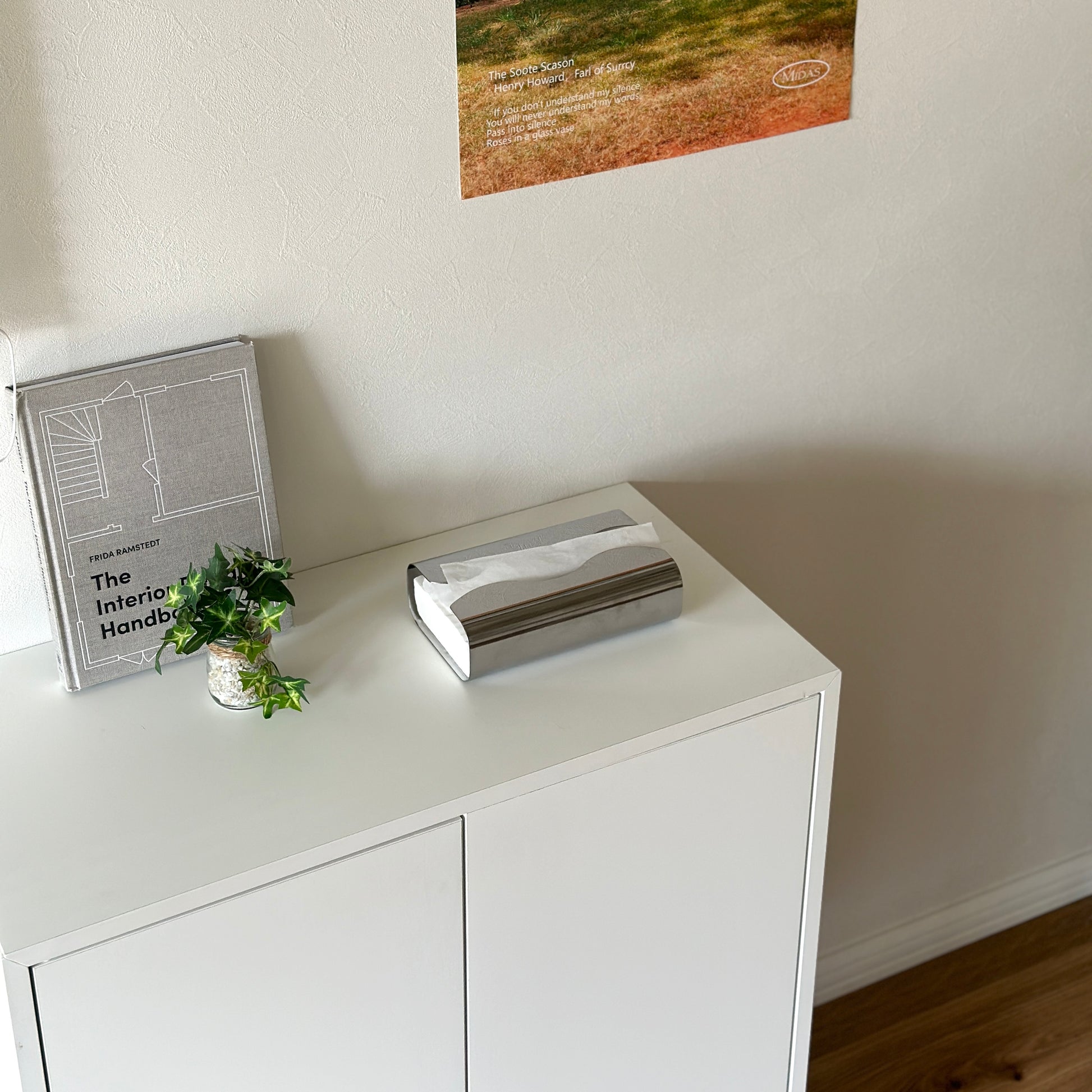 白い棚の上に取り出し口がウェーブデザインのステンレス製ティッシュケースが置かれてある