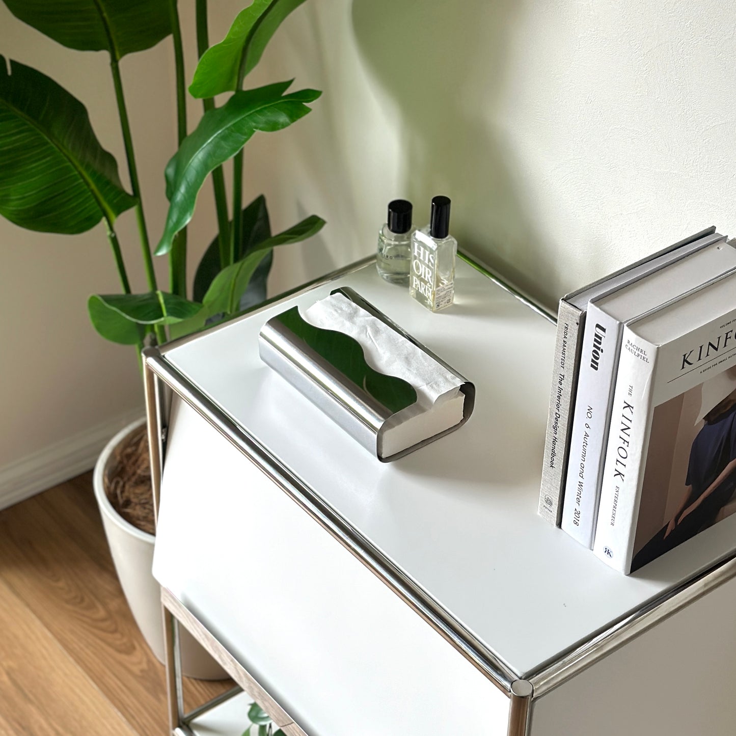 シェルフの上に本と香水と一緒に置かれた取り出し口がウェーブデザインのステンレス製ティッシュケース