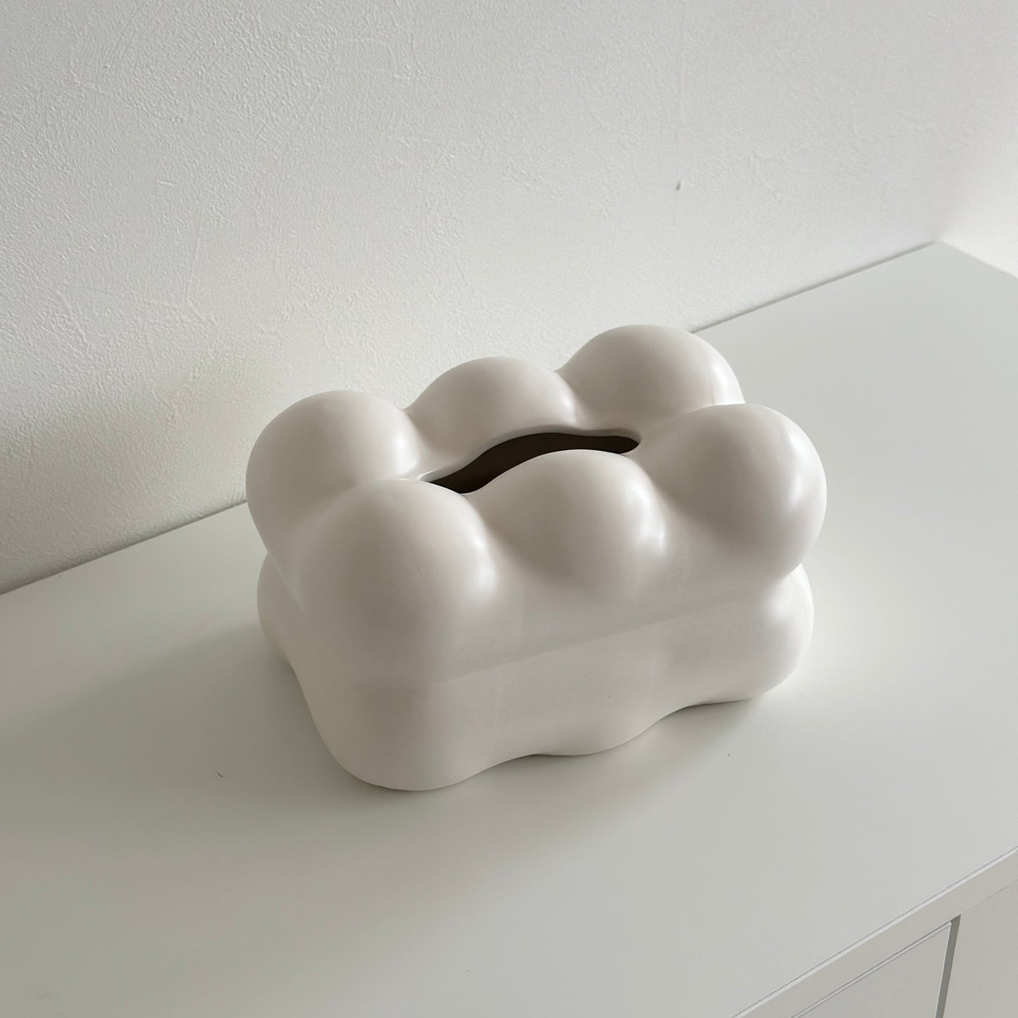 もくもくしたセラミック製の白いティッシュケースがホワイトの棚の上に置かれている様子