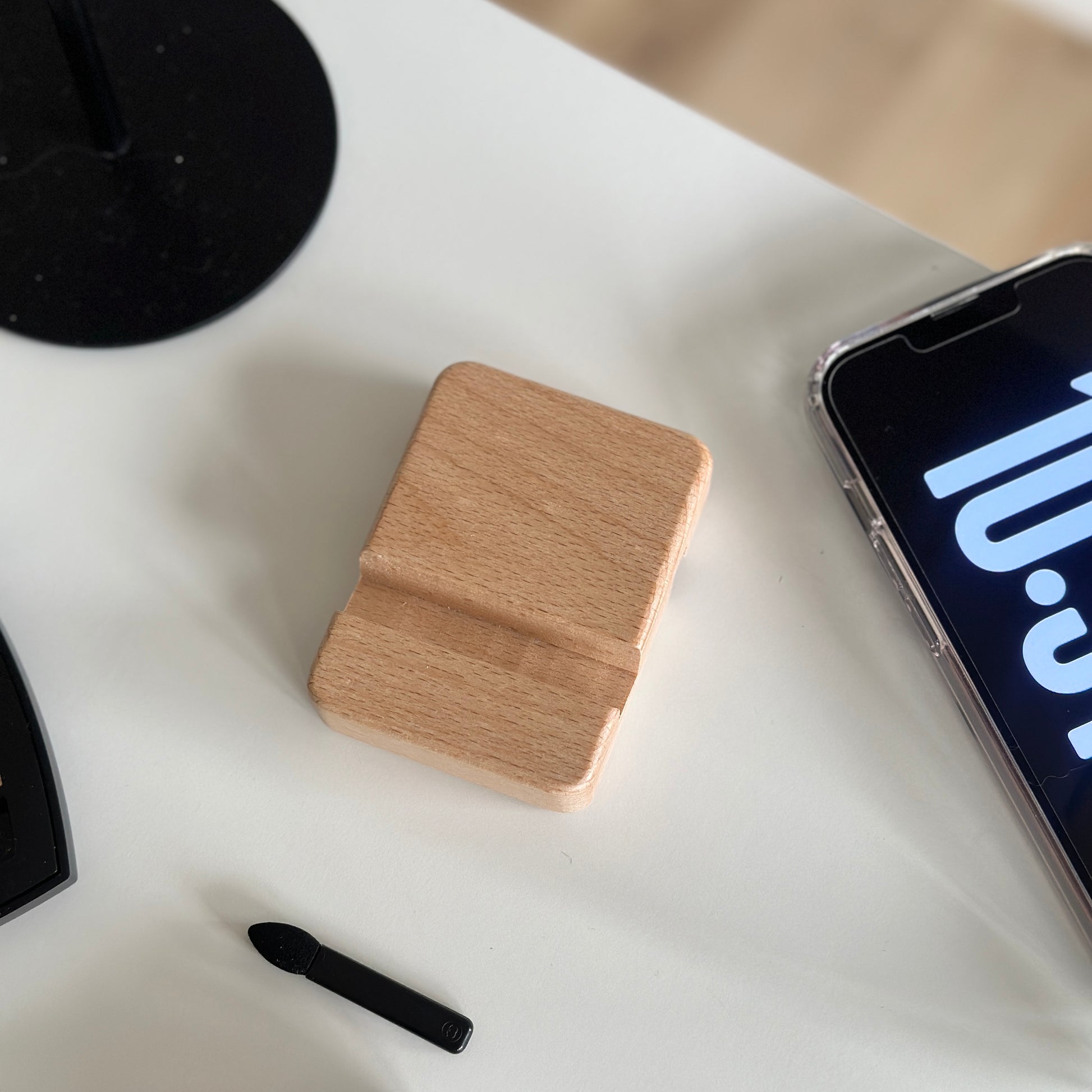木製のスマホスタンドの横にスマホを置いている様子