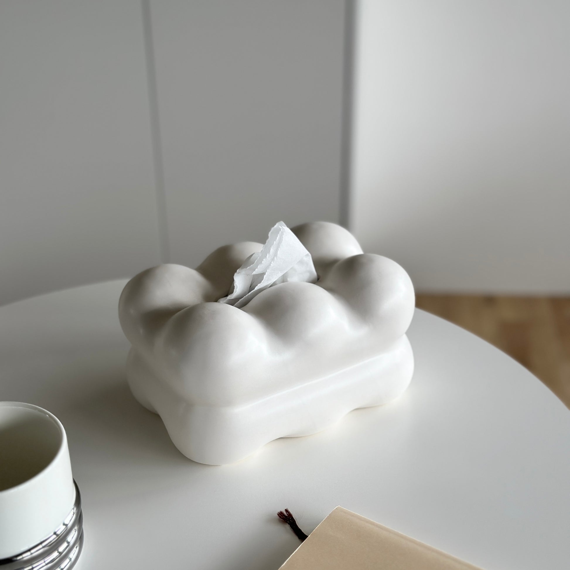 もくもくしたセラミック製の白いティッシュケースがホワイトのテーブルの上に置かれている様子