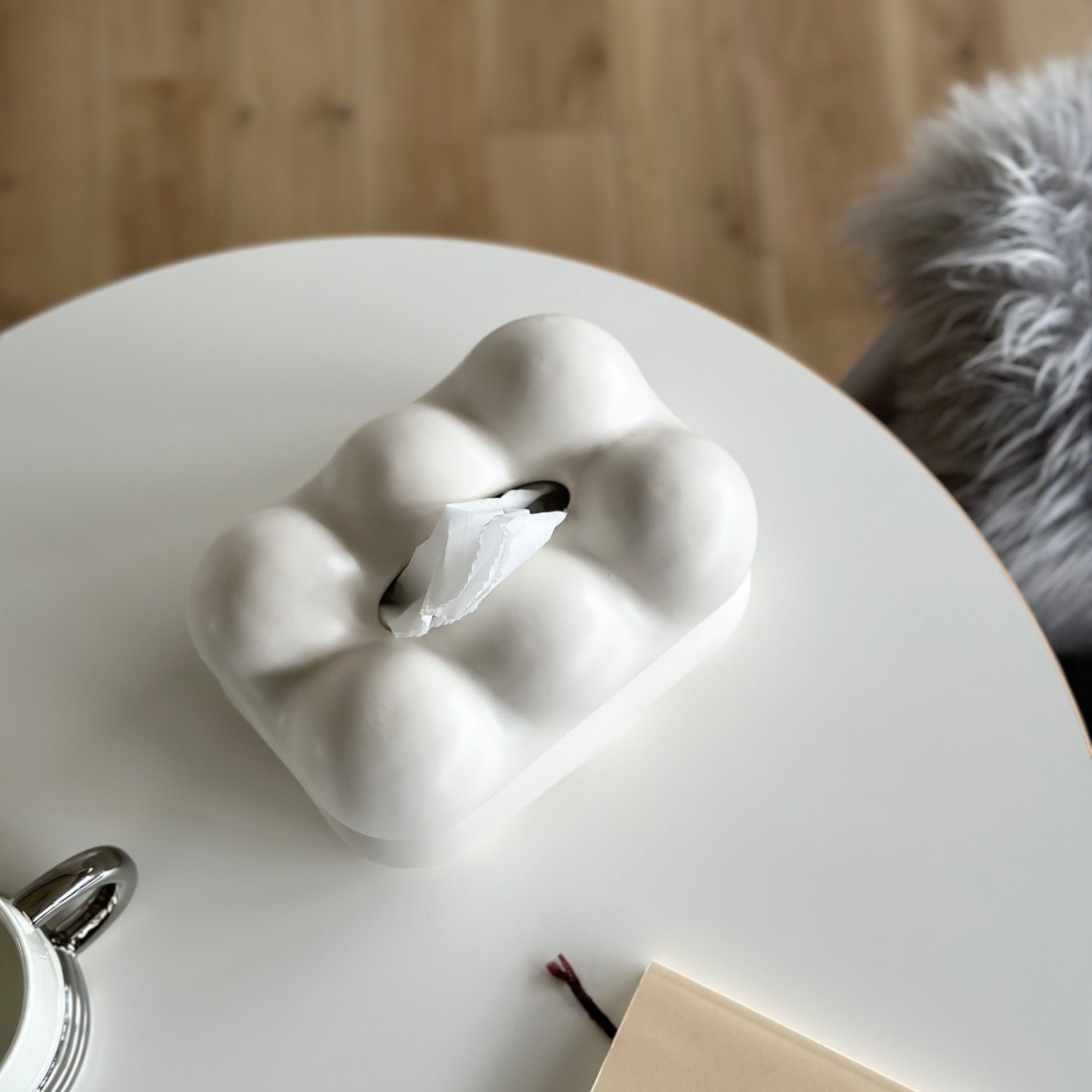 もくもくしたセラミック製の白いティッシュケースがホワイトのテーブルの上に置かれている様子
