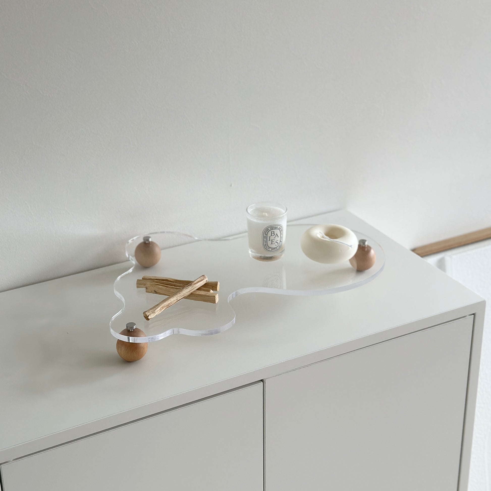 ウッドボールの脚がついたアクリルトレイの上にパロサントやキャンドルを置いている様子