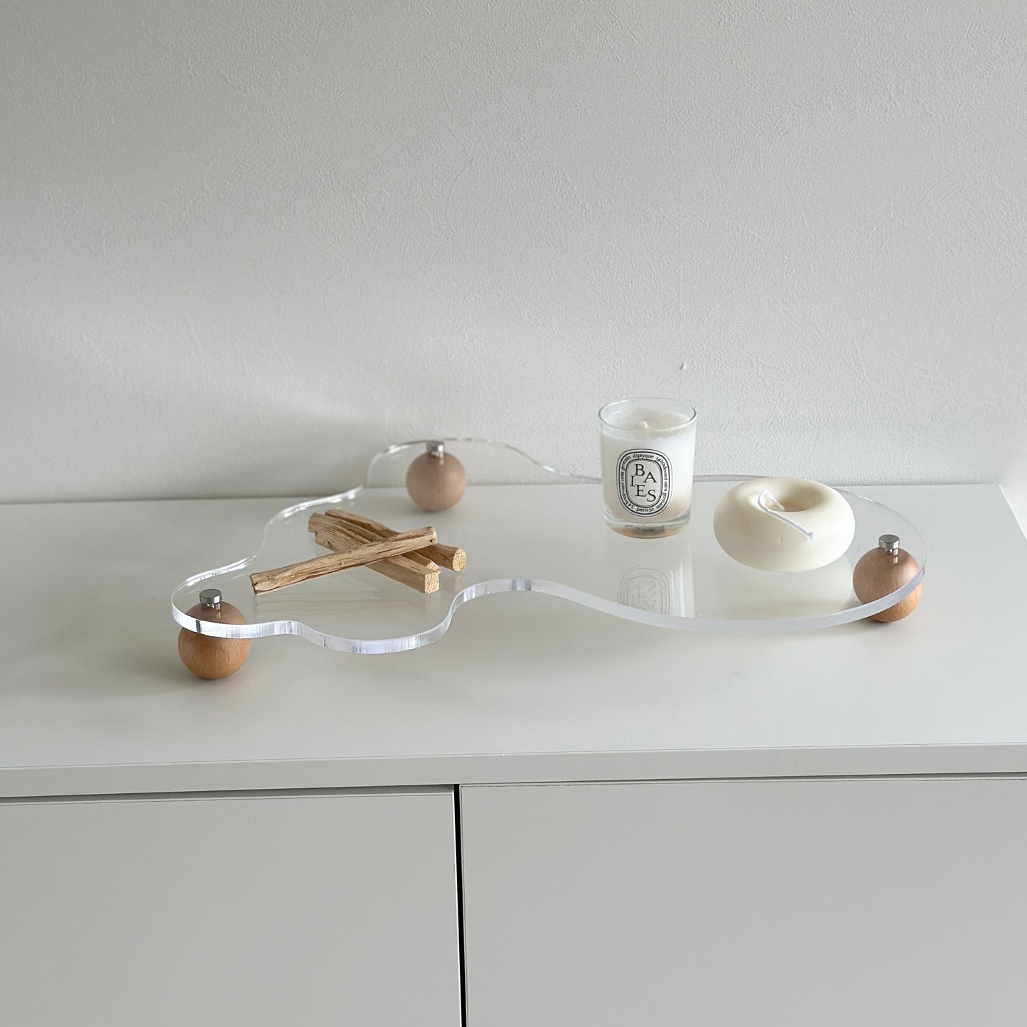 ウッドボールの脚がついたアクリルトレイの上にパロサントやキャンドルを置いている様子