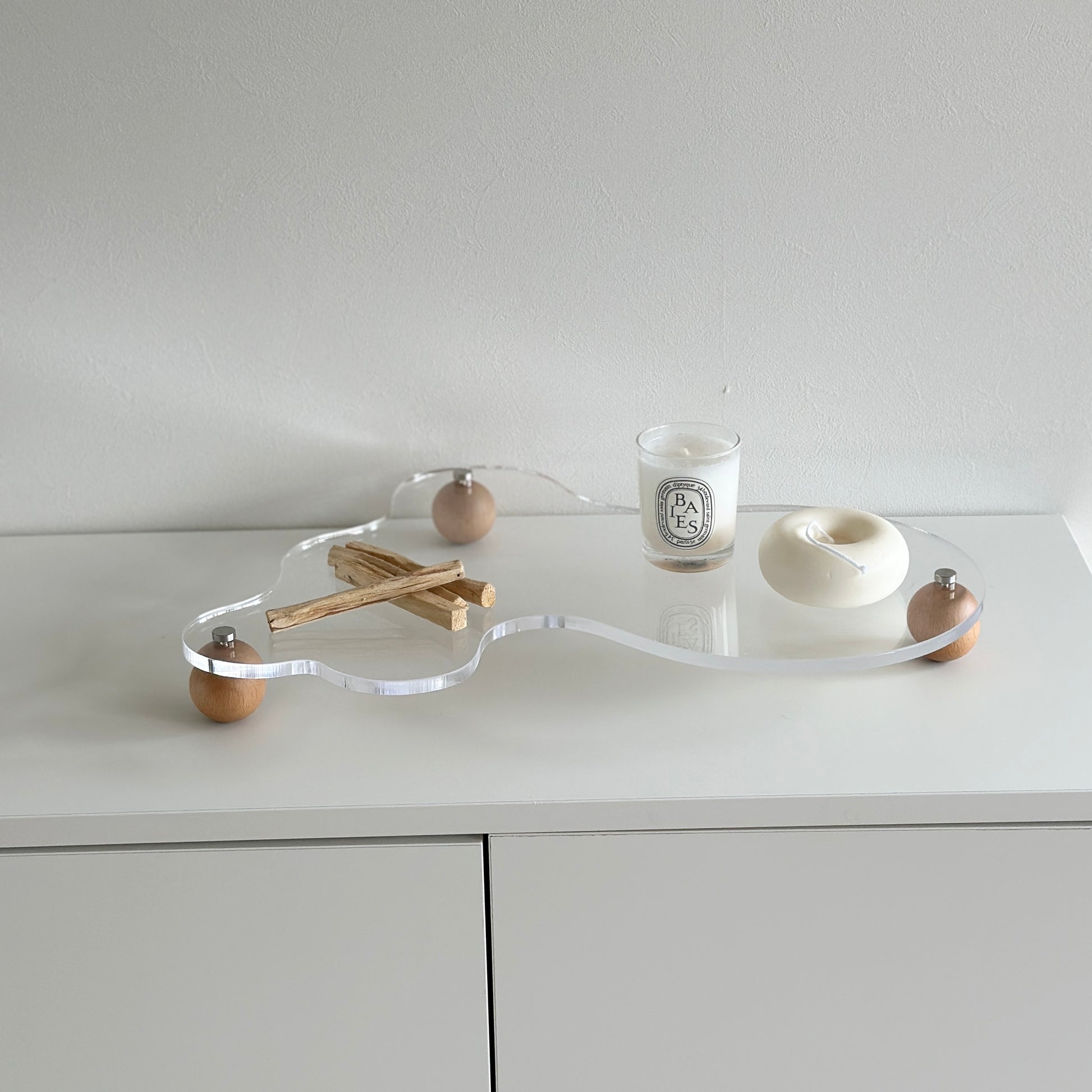 ウッドボールの脚がついたアクリルトレイの上にパロサントやキャンドルを置いている様子