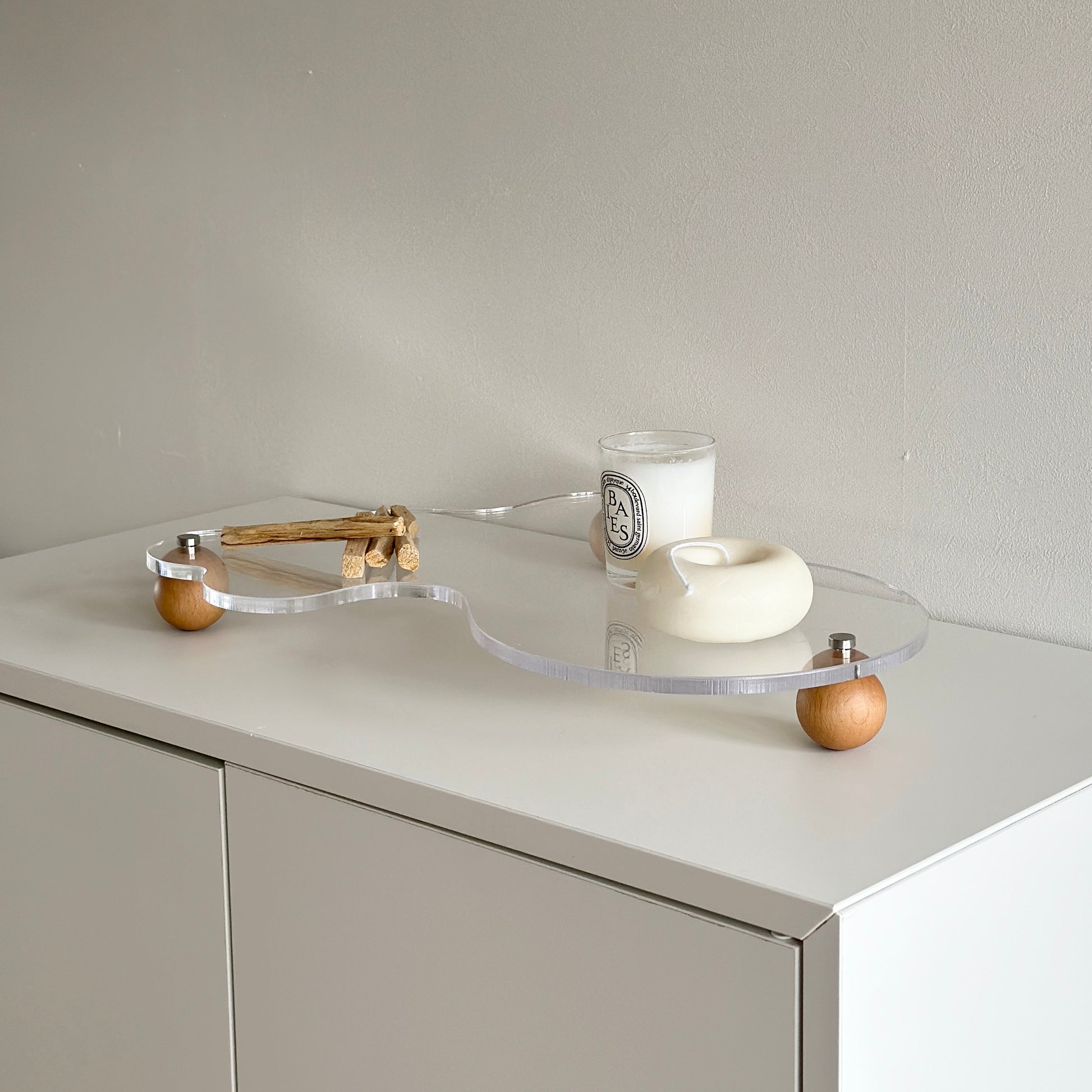 ウッドボールの脚がついたアクリルトレイの上にパロサントやキャンドルを置いている様子