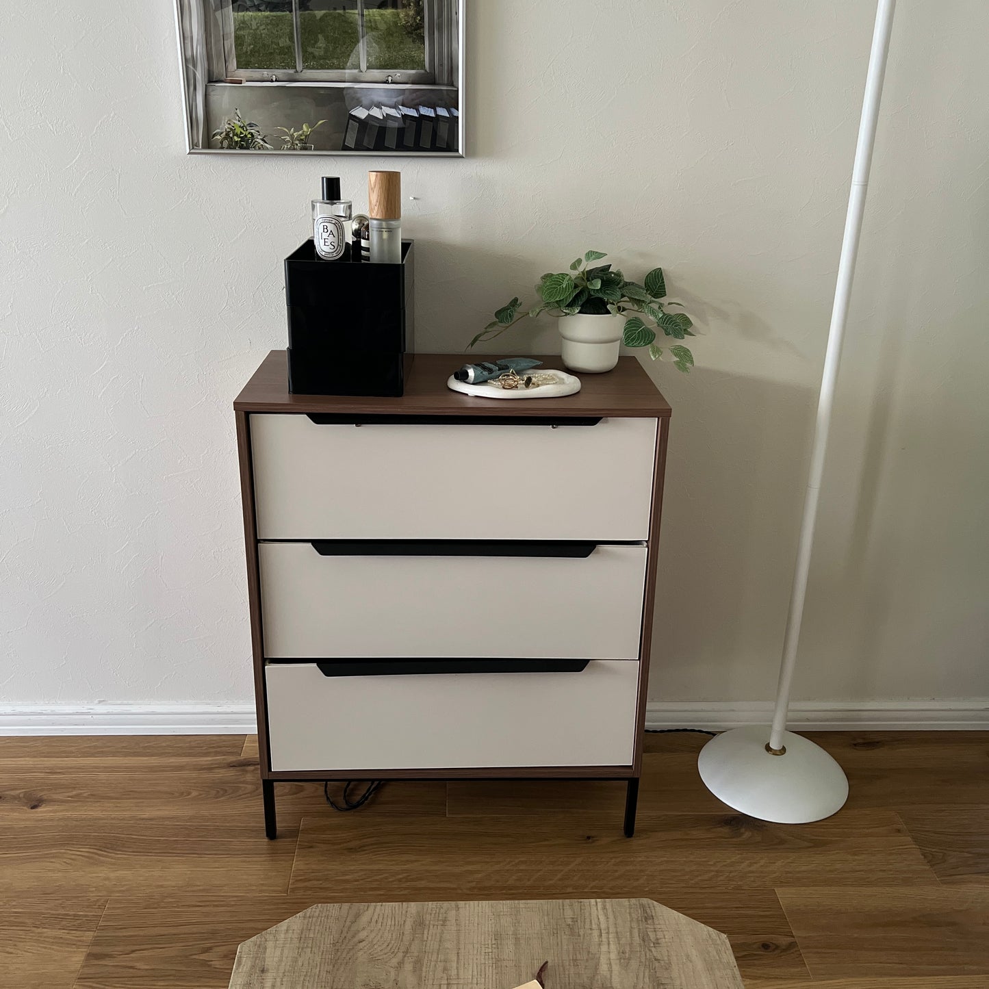 部屋の中でチェストの上に黒い3段の収納ケースが乗っている様子