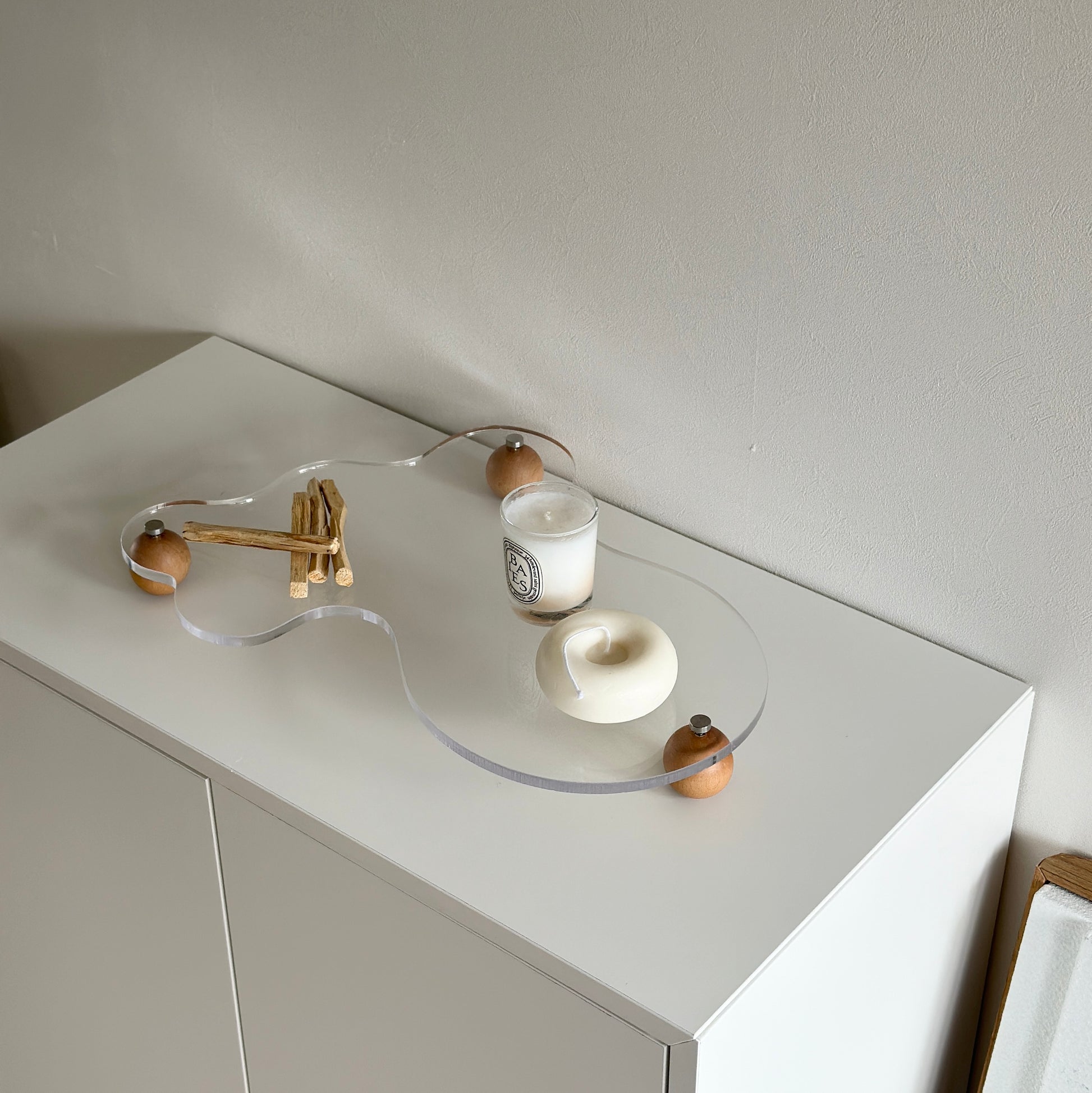 ウッドボールの脚がついたアクリルトレイの上にパロサントやキャンドルを置いている様子