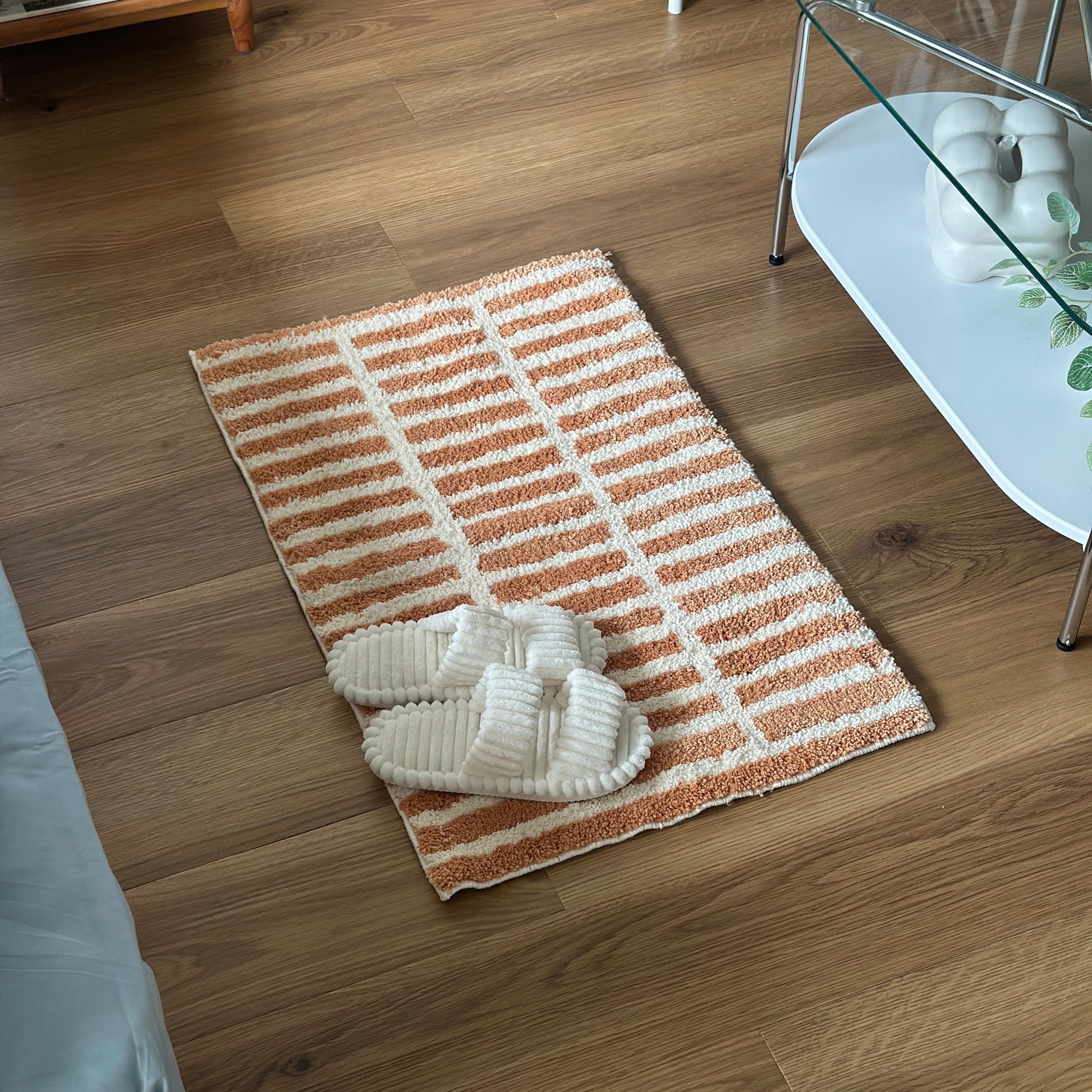 オレンジとホワイトのタイルライン柄のミニラグにホワイトのスリッパが置かれている様子