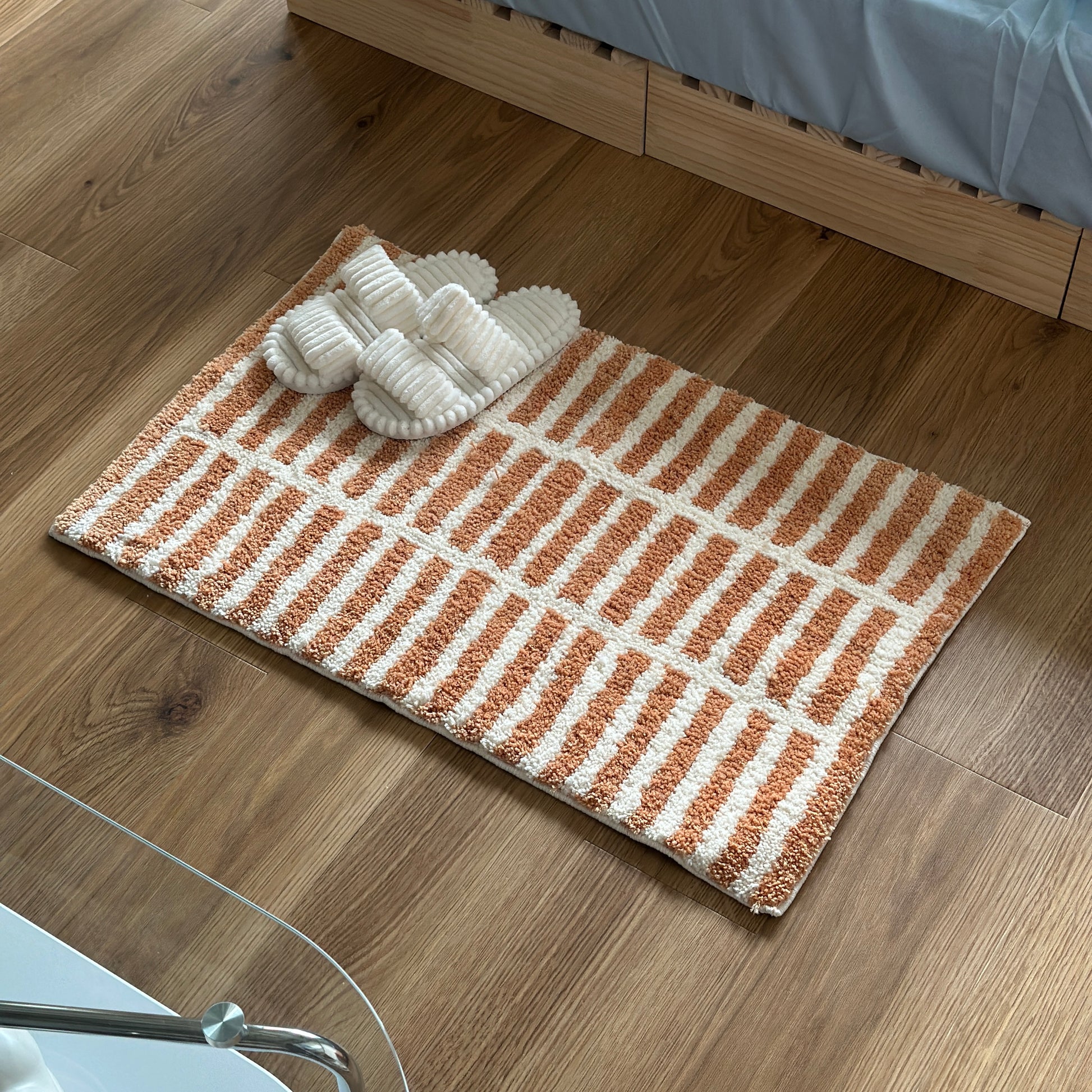 オレンジとホワイトのタイルライン柄のミニラグにホワイトのスリッパが置かれている様子