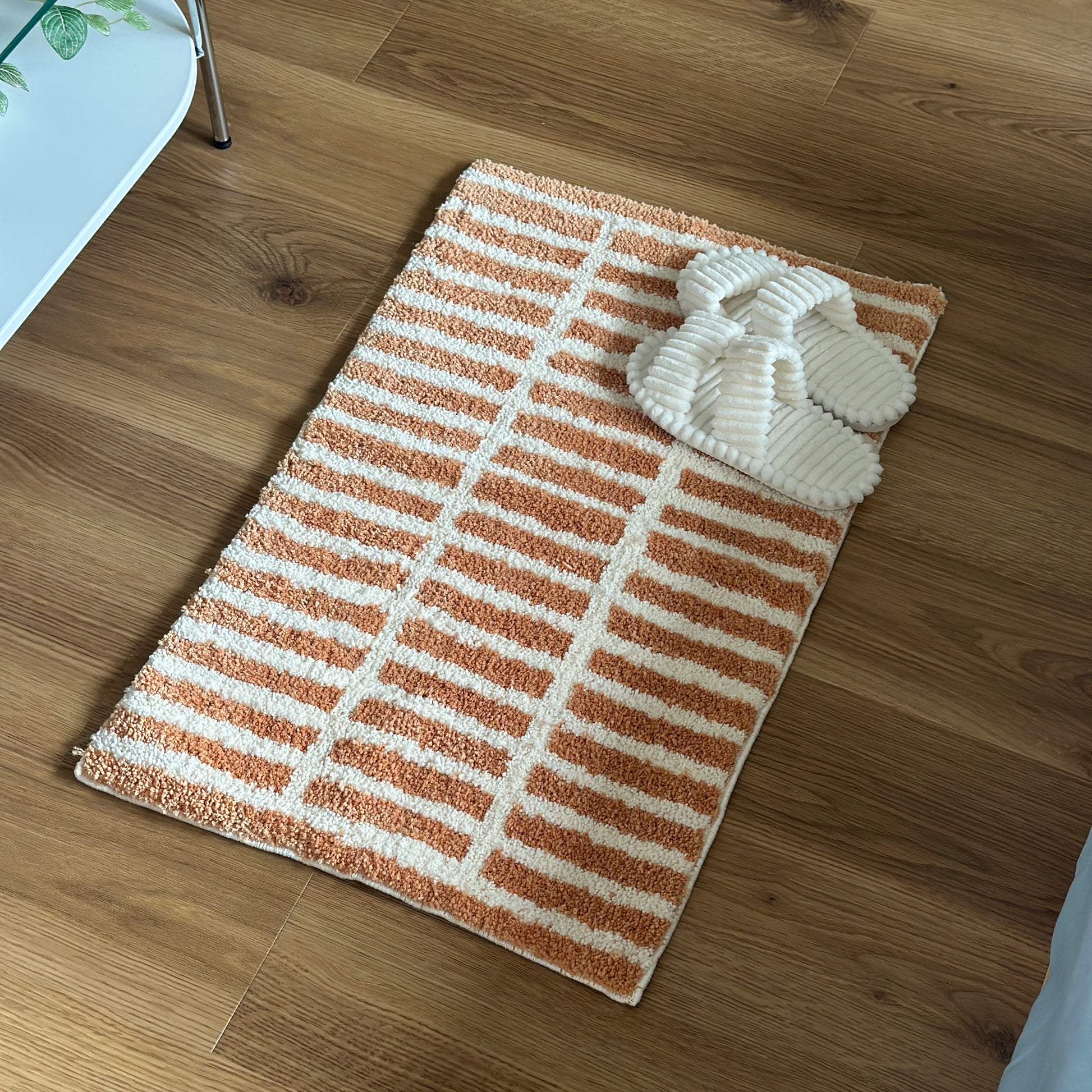 オレンジとホワイトのタイルライン柄のミニラグにホワイトのスリッパが置かれている様子