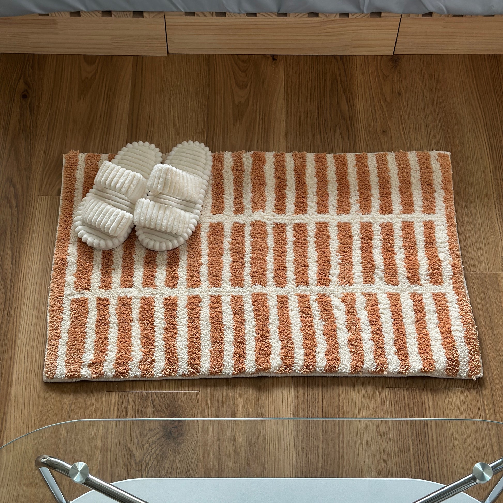 オレンジとホワイトのタイルライン柄のミニラグにホワイトのスリッパが置かれている様子