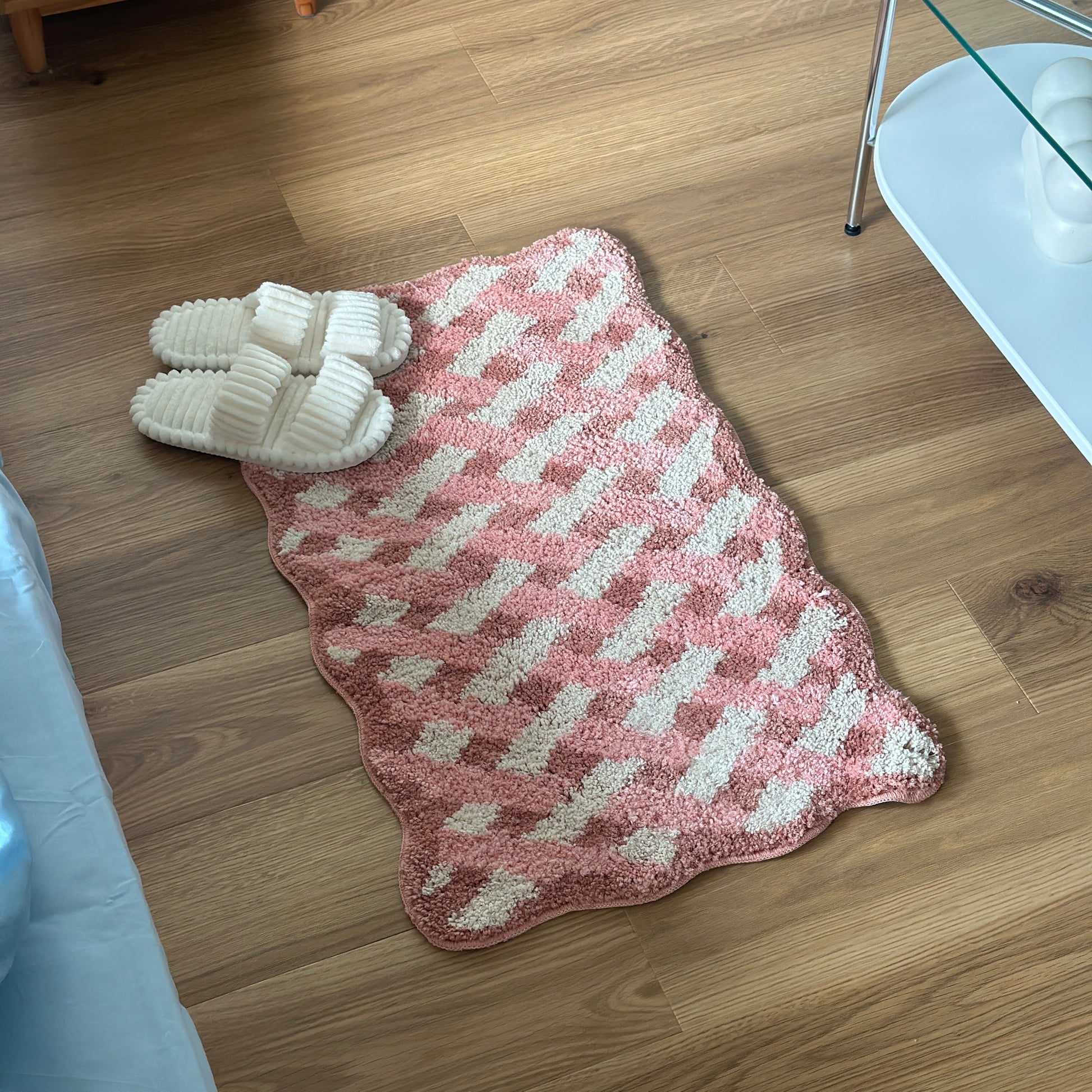 ピンクのウェーブクロス柄のミニラグにホワイトのスリッパを置いている様子