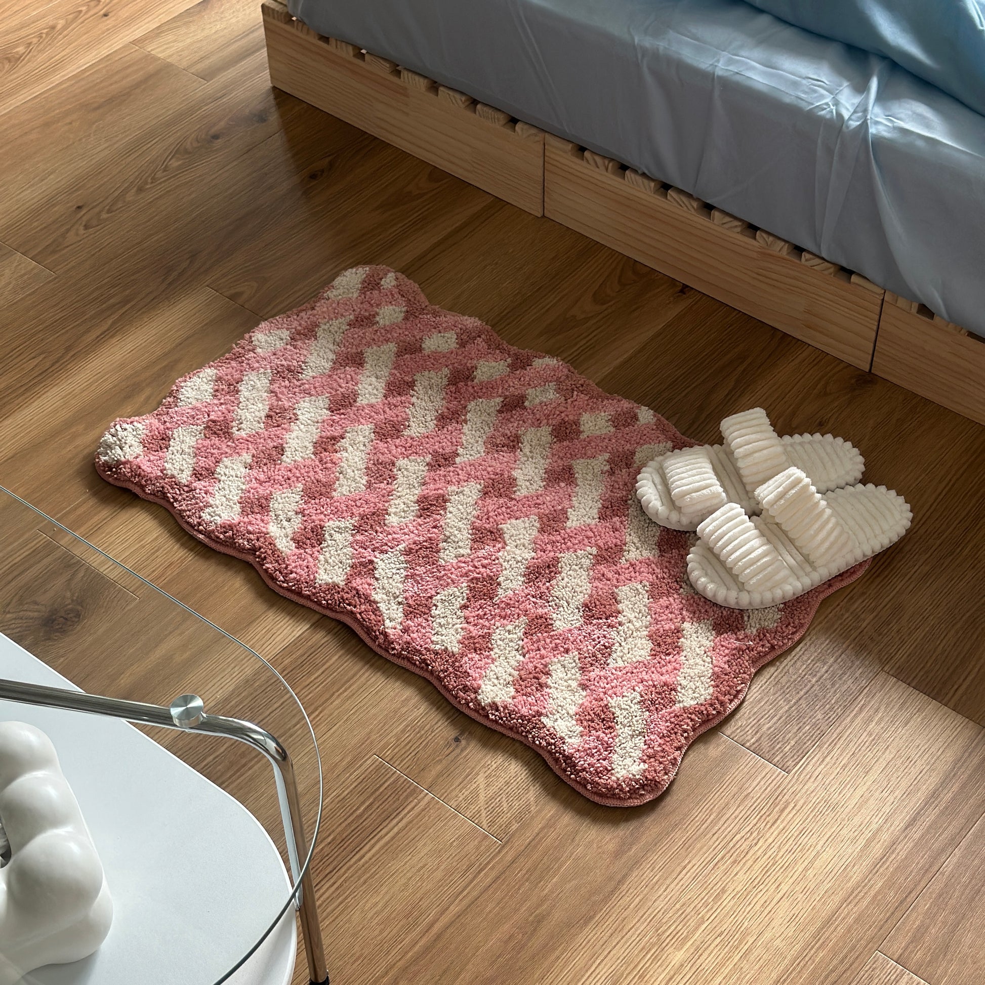 ピンクのウェーブクロス柄のミニラグにホワイトのスリッパが置かれている様子