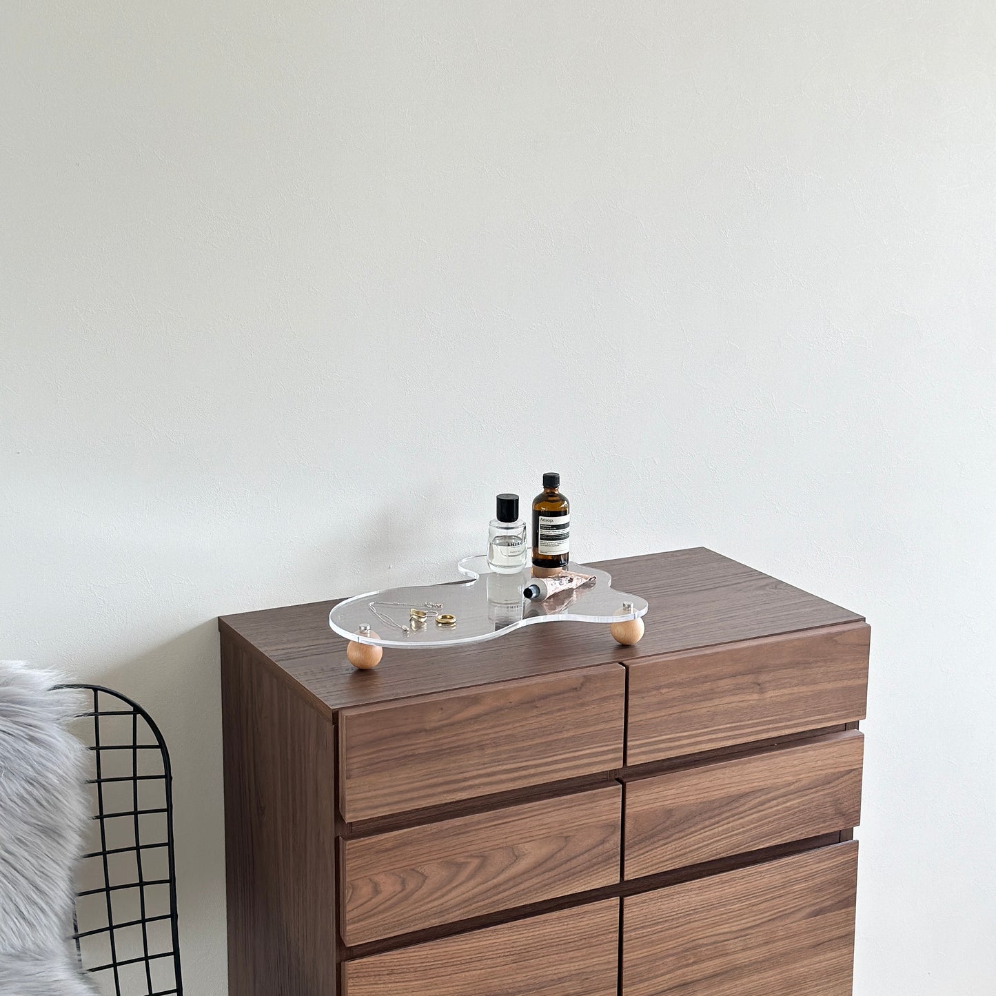 ウッドボールの脚がついたアクリルトレイの上にアクセサリーと小物類を置いている様子