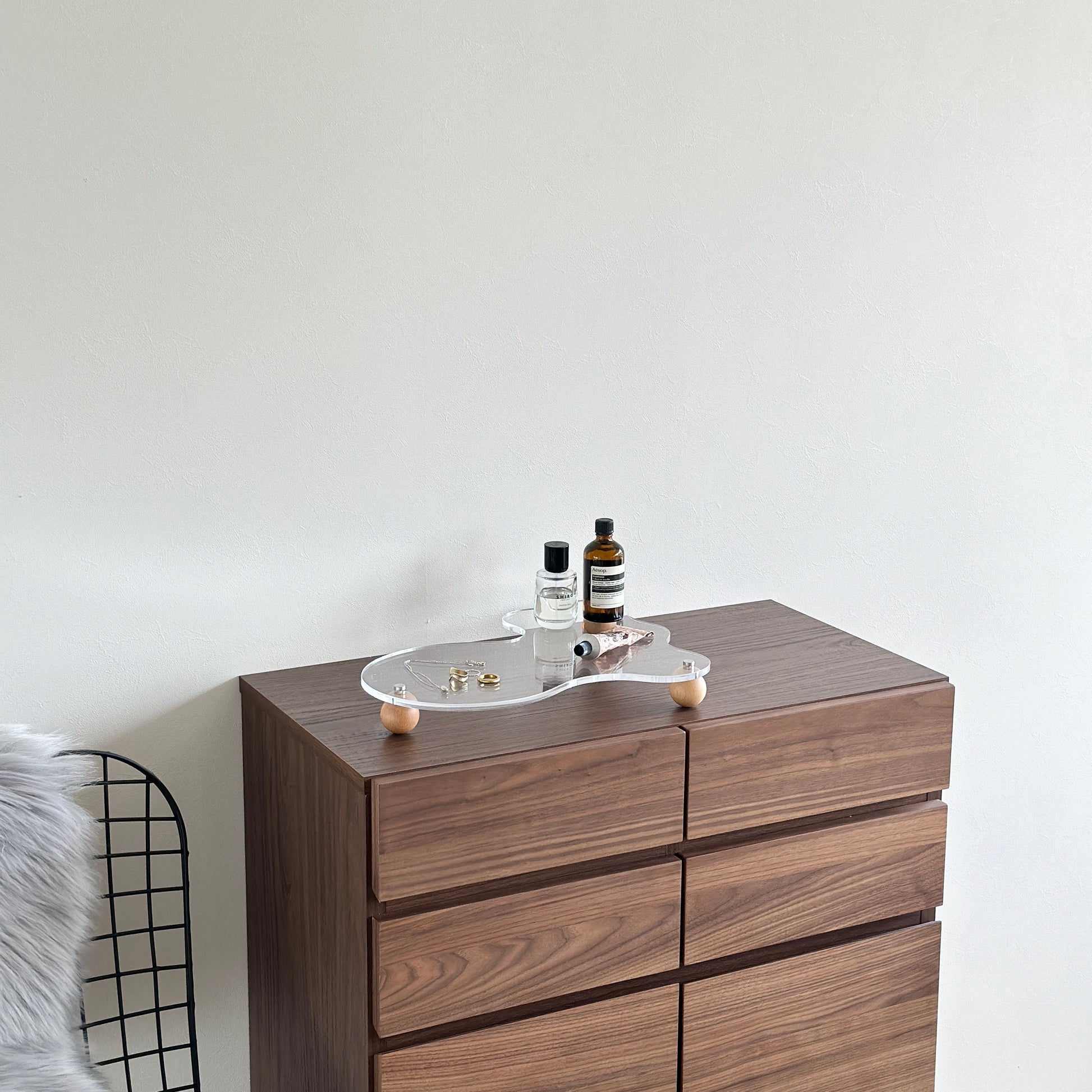 ウッドボールの脚がついたアクリルトレイの上にアクセサリーと小物類を置いている様子