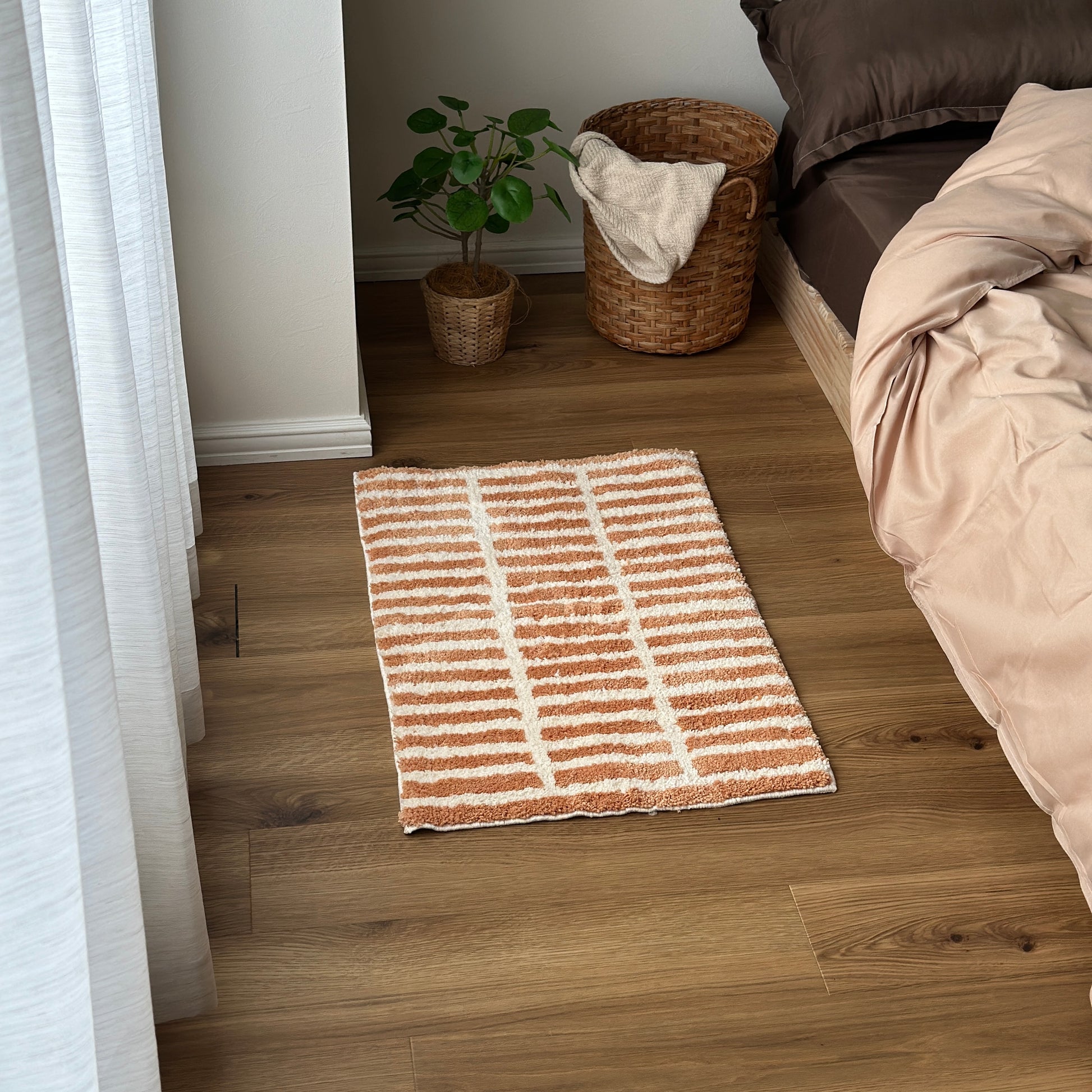 オレンジとホワイトのタイルライン柄のミニラグをベッド横に敷いている様子