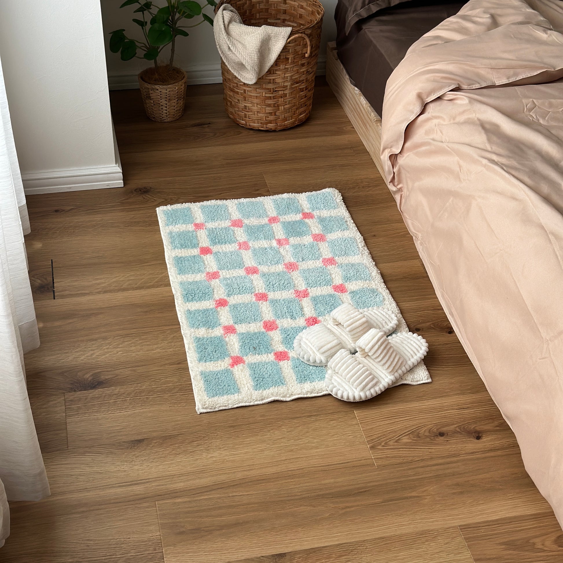 ライトブルーとピンクのスクエア柄のミニラグをベッド横に敷いている様子