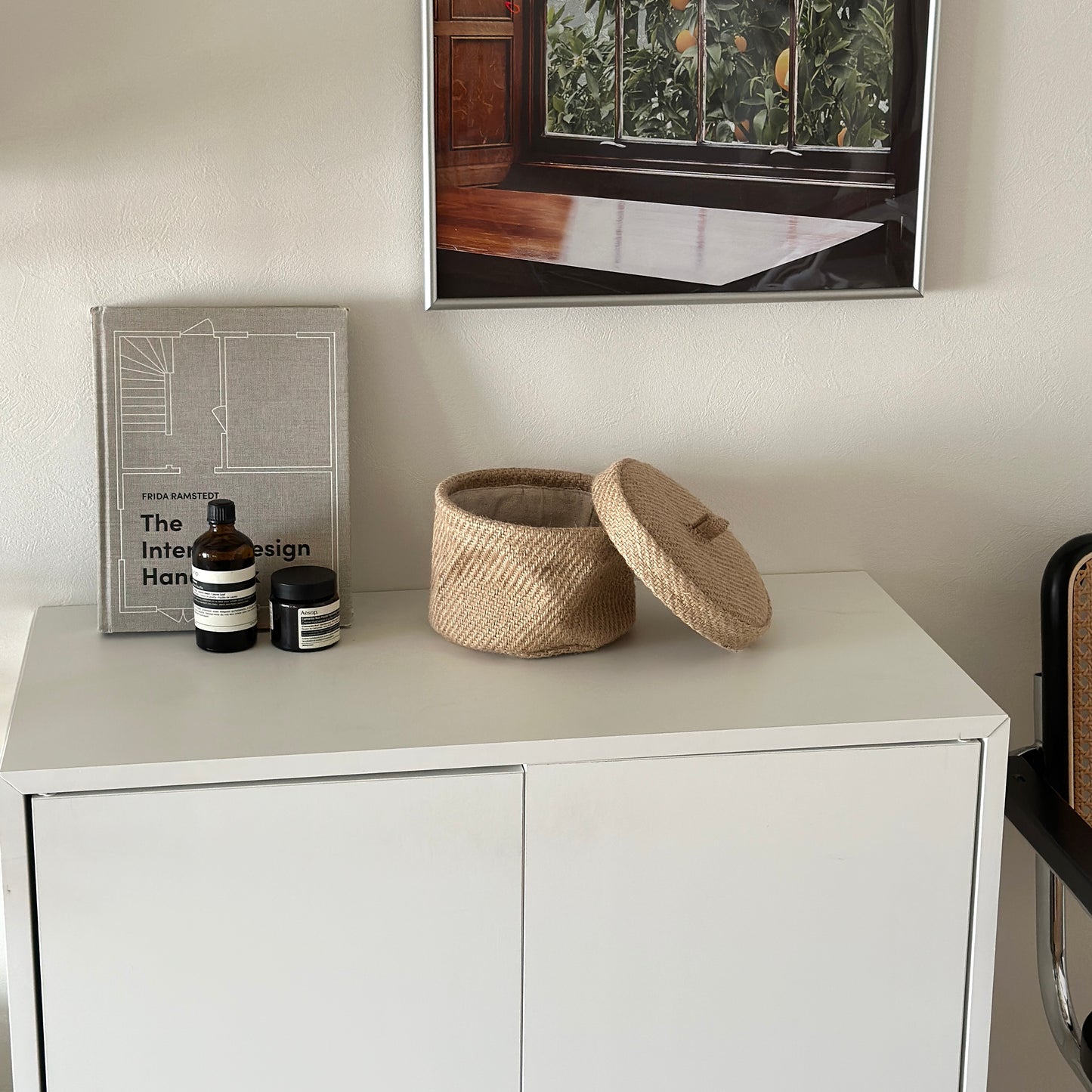 白い棚の上に蓋が開いた状態のリネンの蓋付きバスケットが置かれてある