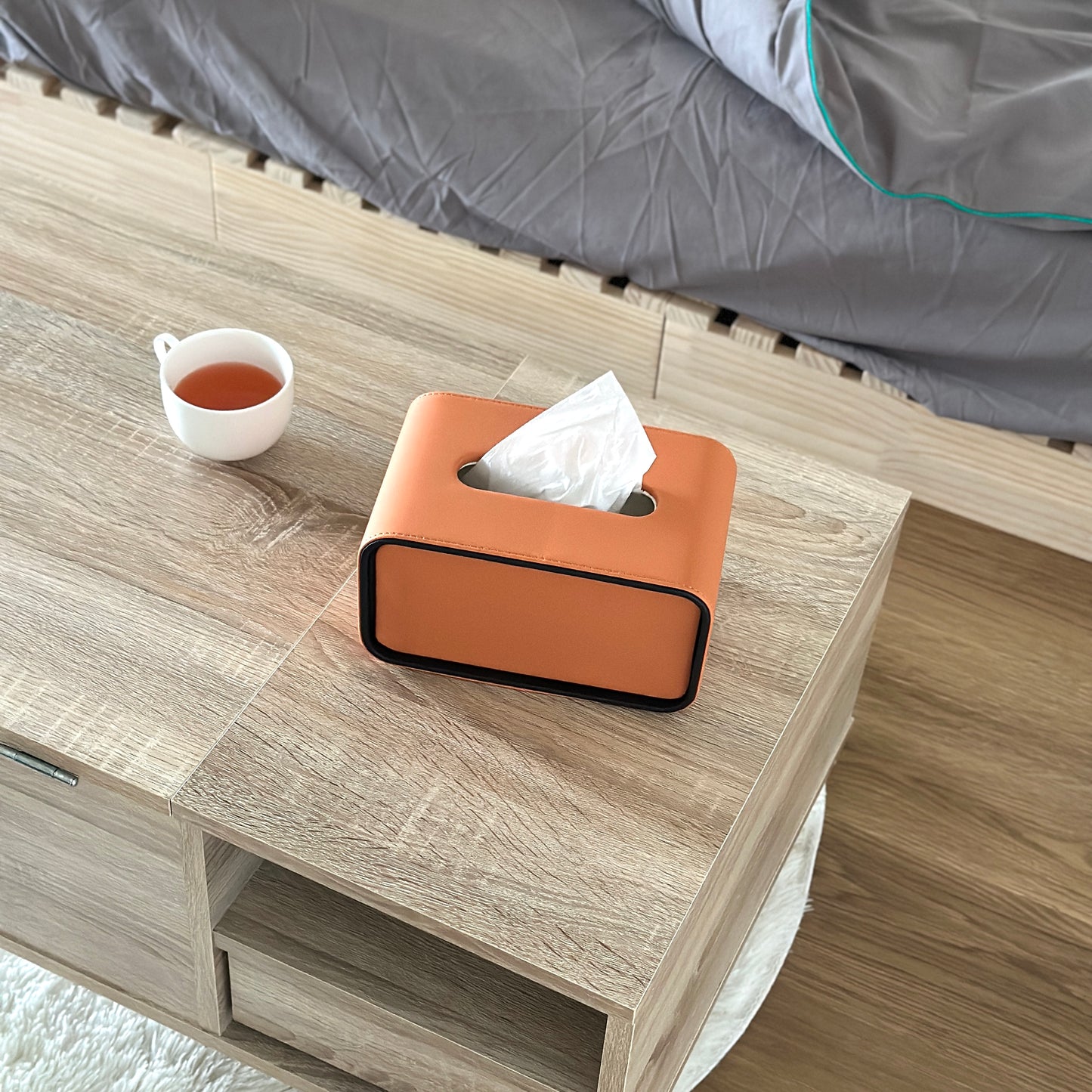 オレンジ色のレザー調の見た目が特徴のティッシュケースがテーブルの上に置かれている