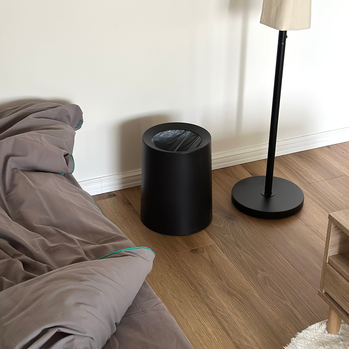 ブラックの二重構造のゴミ箱がベッドの横に置かれている様子