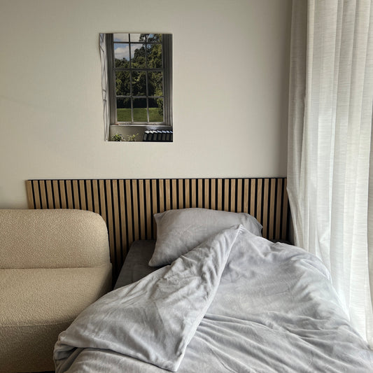 6畳の空間にベッドとソファと吸音パネルが置いてある部屋